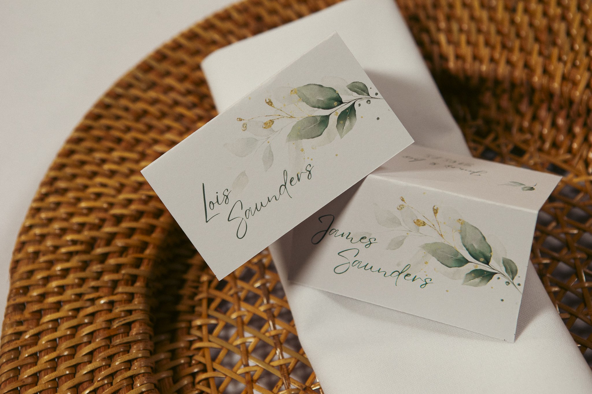 Wedding place cards with the names Lois Saunders and James Saunders on a rattan chair