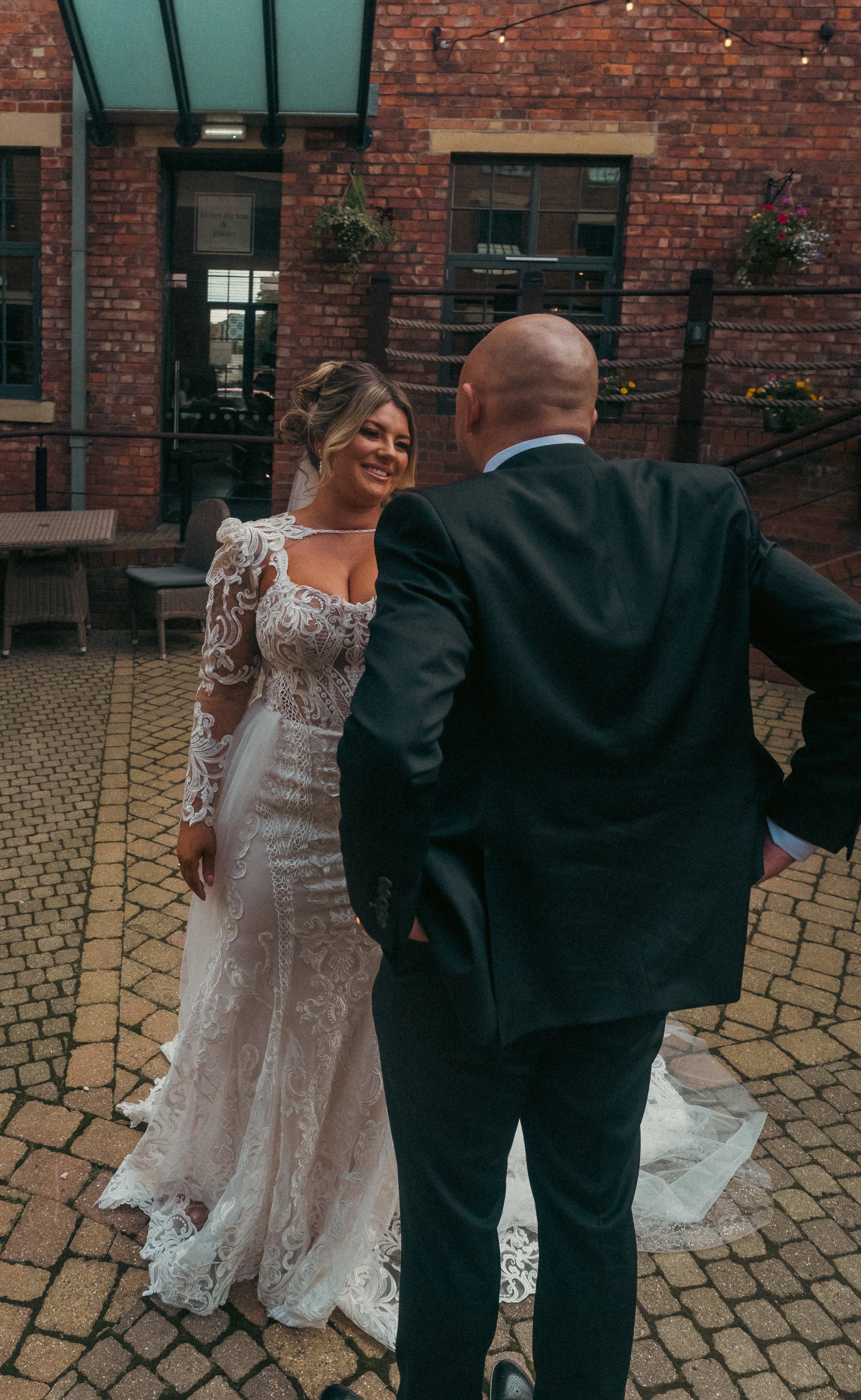 Bride and groom exchanging vows or speaking to each other outdoors on a cobblestone patio at their wedding reception.
