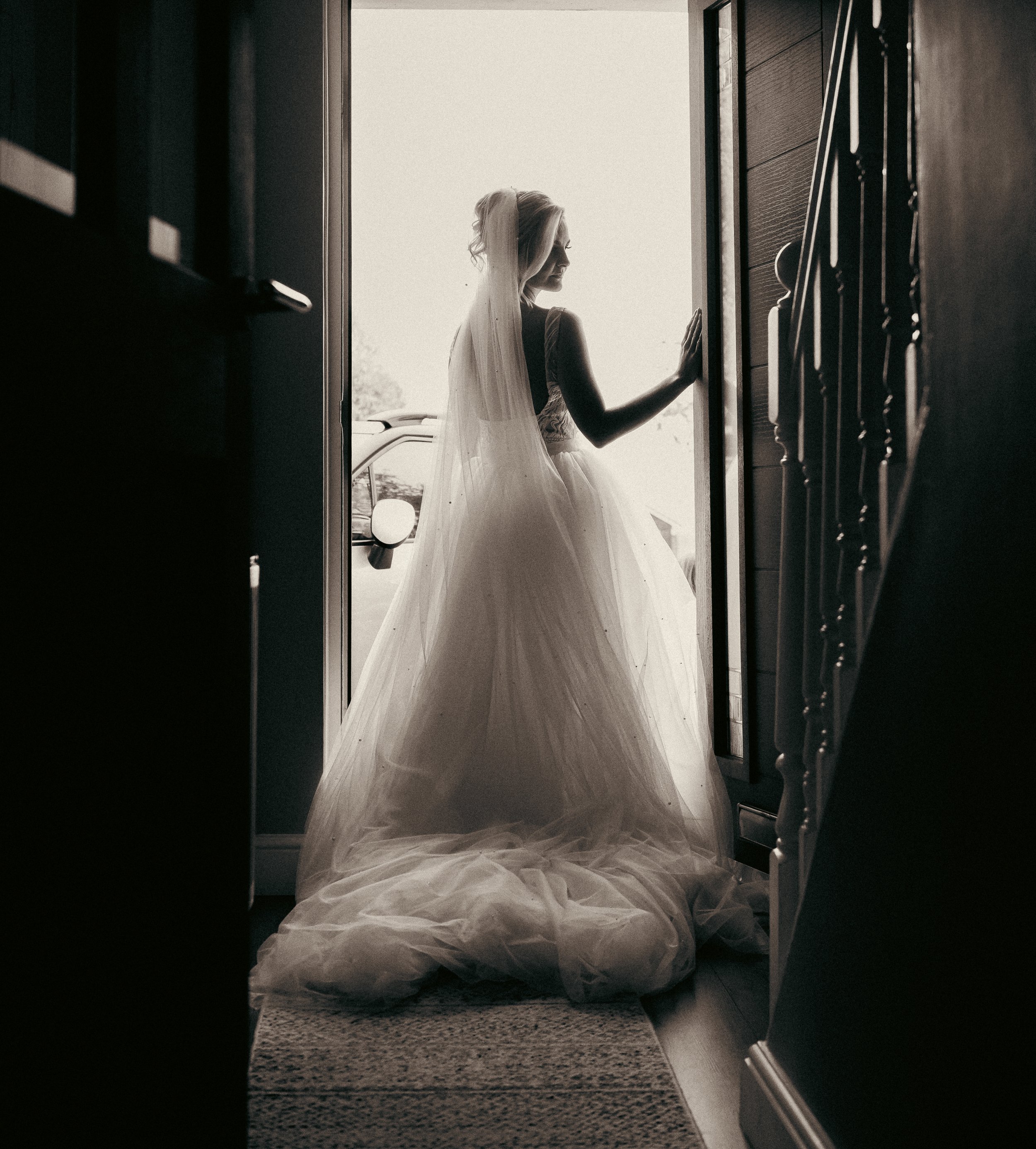 A silhouette of a bride in a wedding gown standing in a doorway, with light shining from outside.