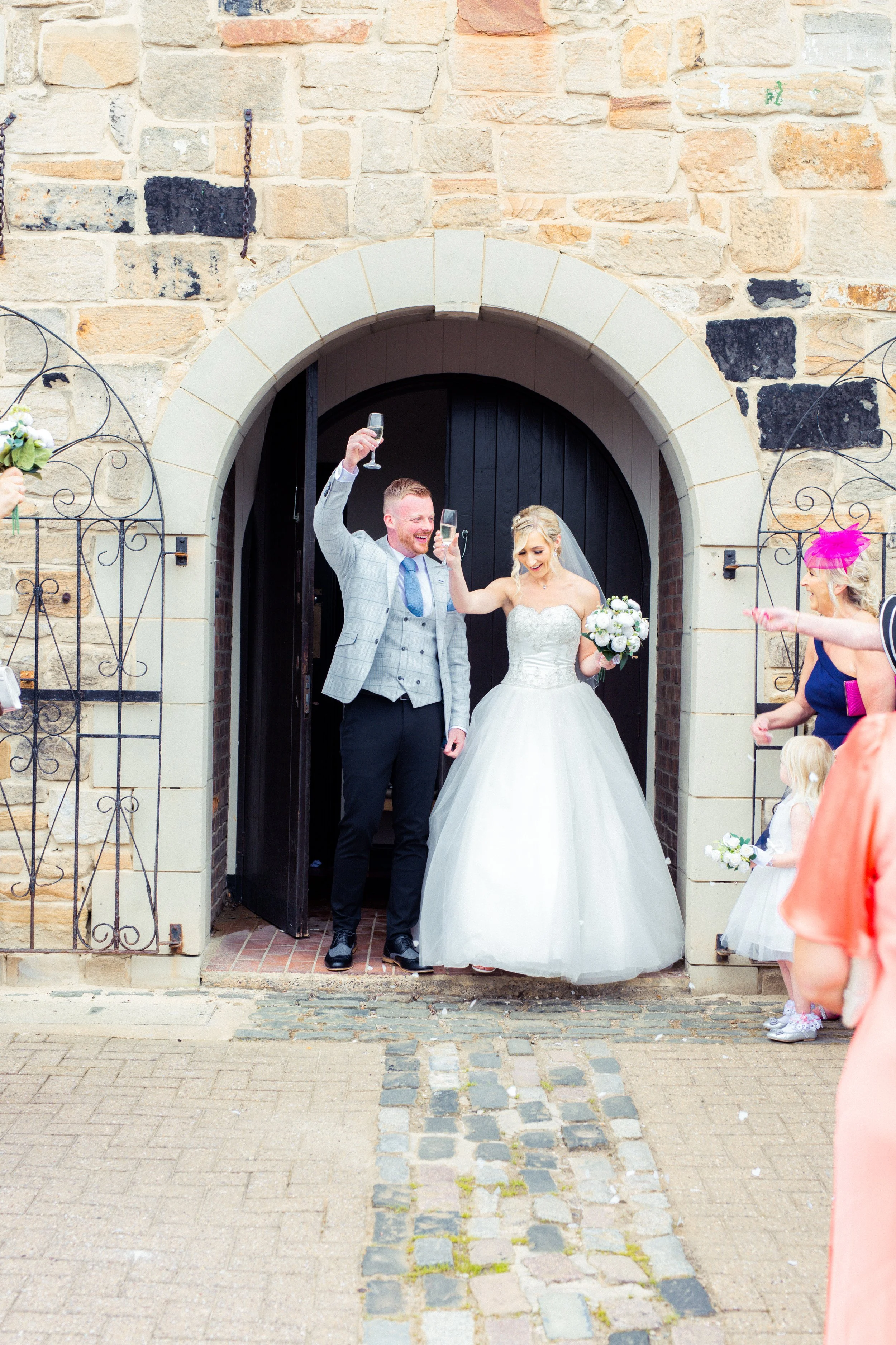 A bride and groom celebrating with champagne outside of a church on their wedding day.