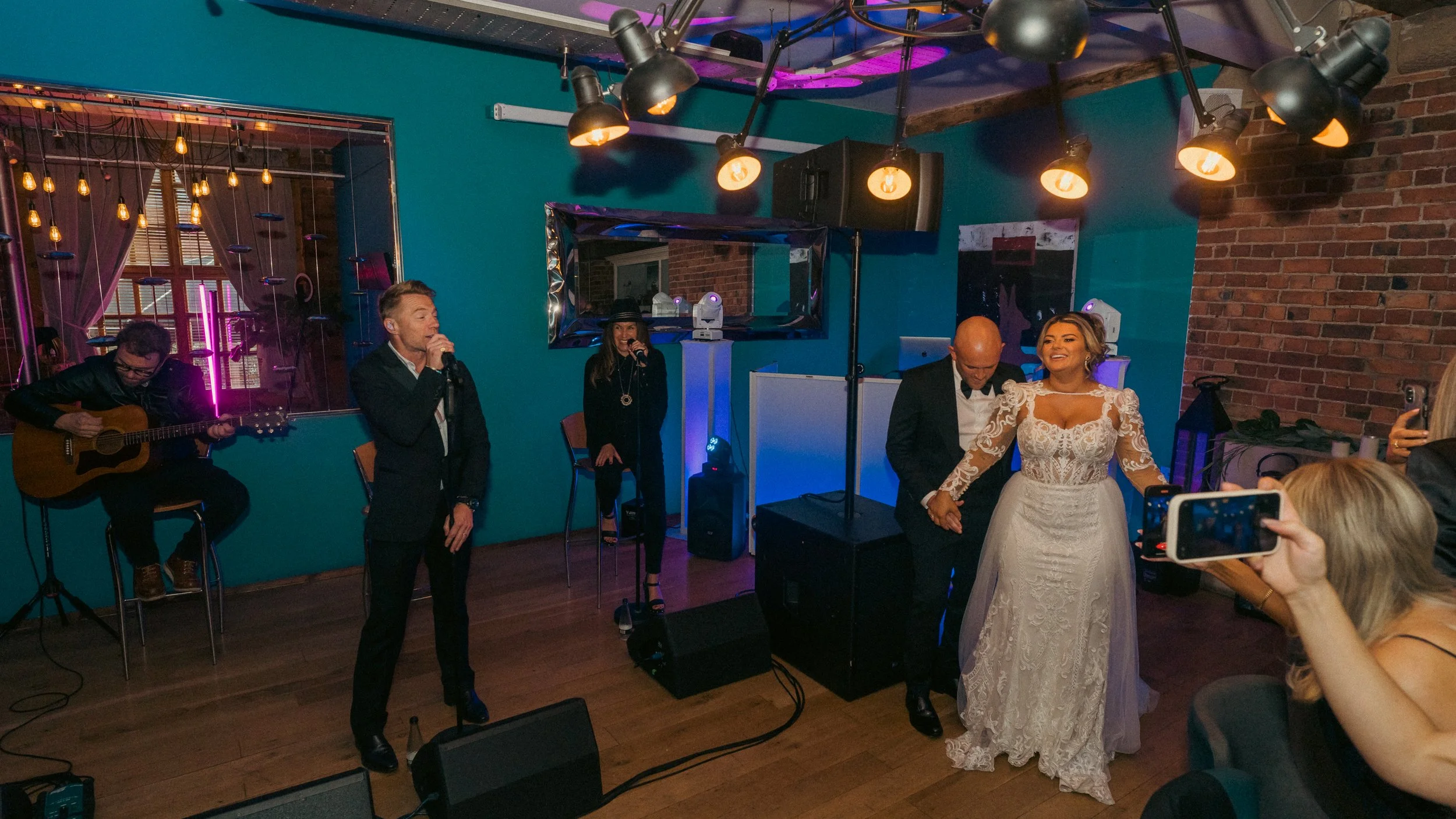 Couple in wedding attire dancing at their wedding reception with band performing on stage in the background