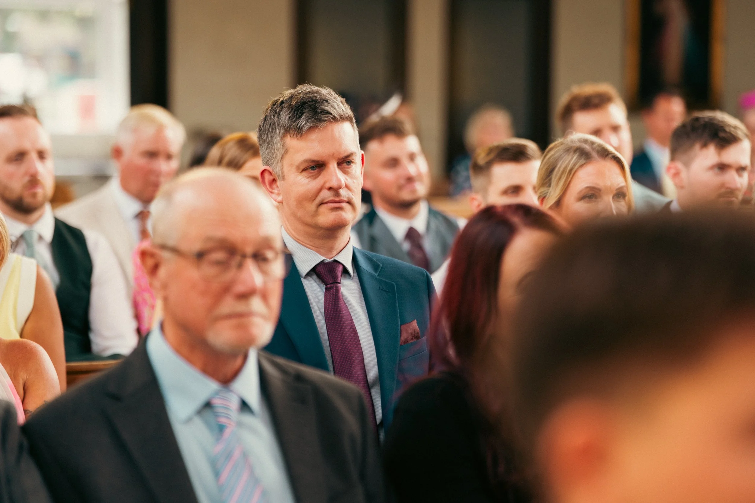 People attending a formal event or conference, sitting and listening attentively.