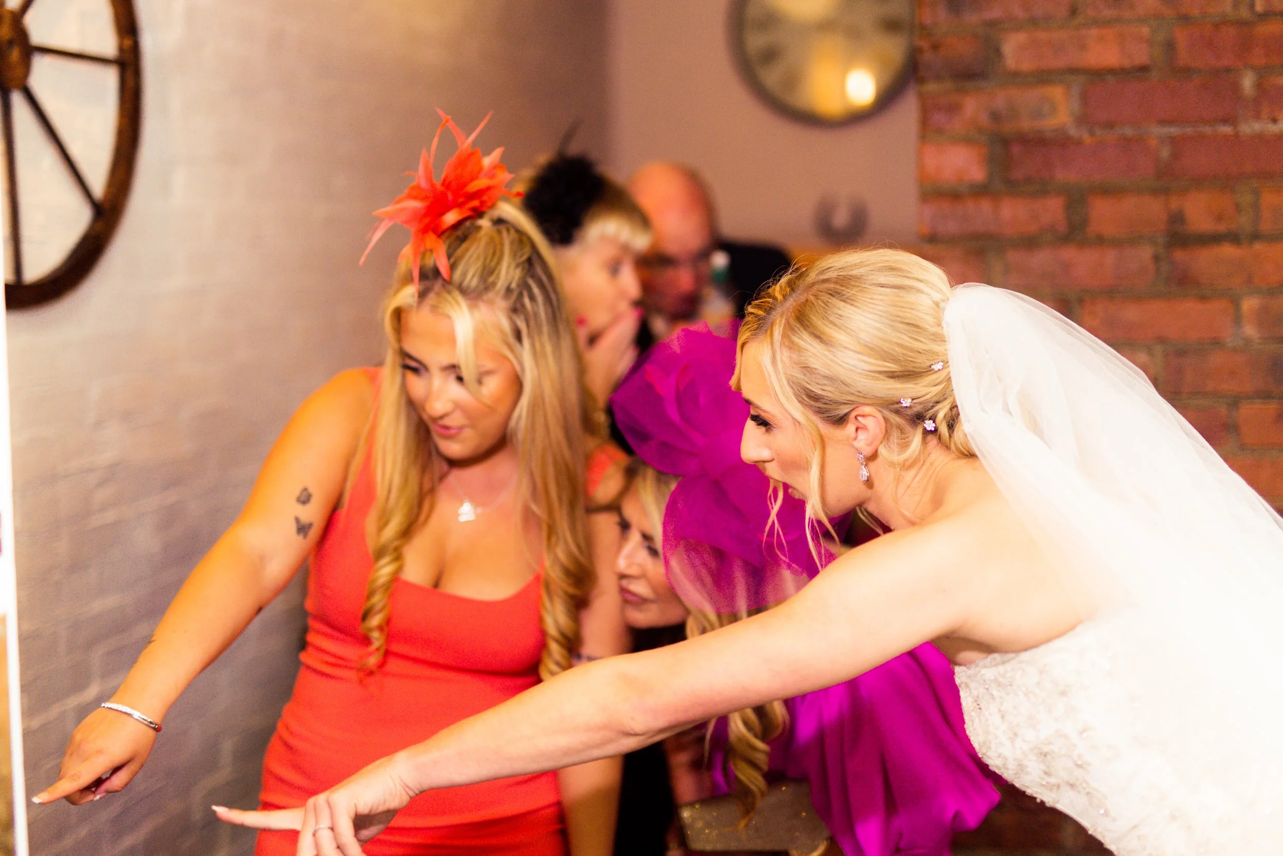 Group of women, one in a wedding dress, and other women in colorful dresses, celebrating at a wedding reception.