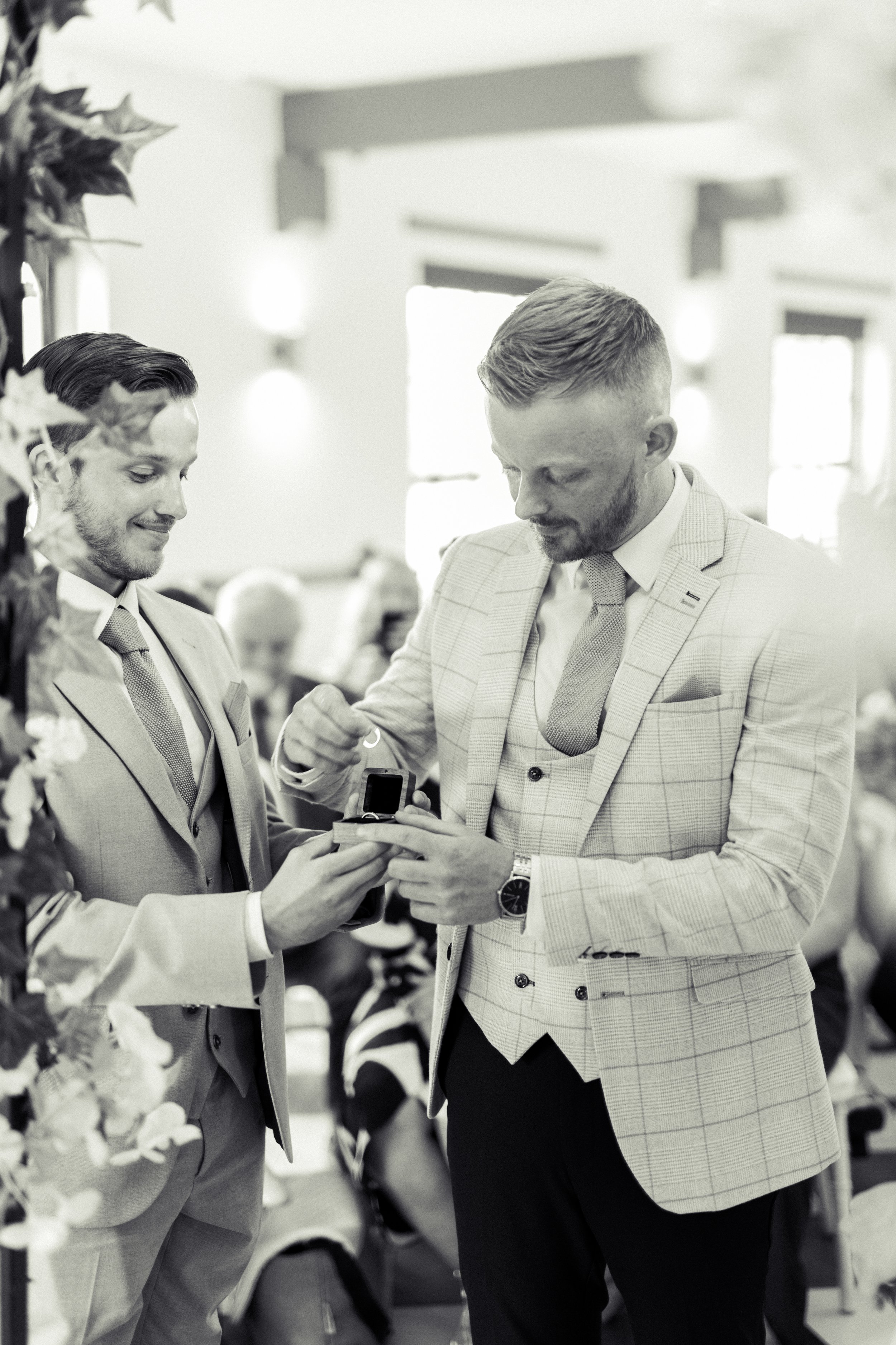 Two men in suits exchange rings during a wedding ceremony.