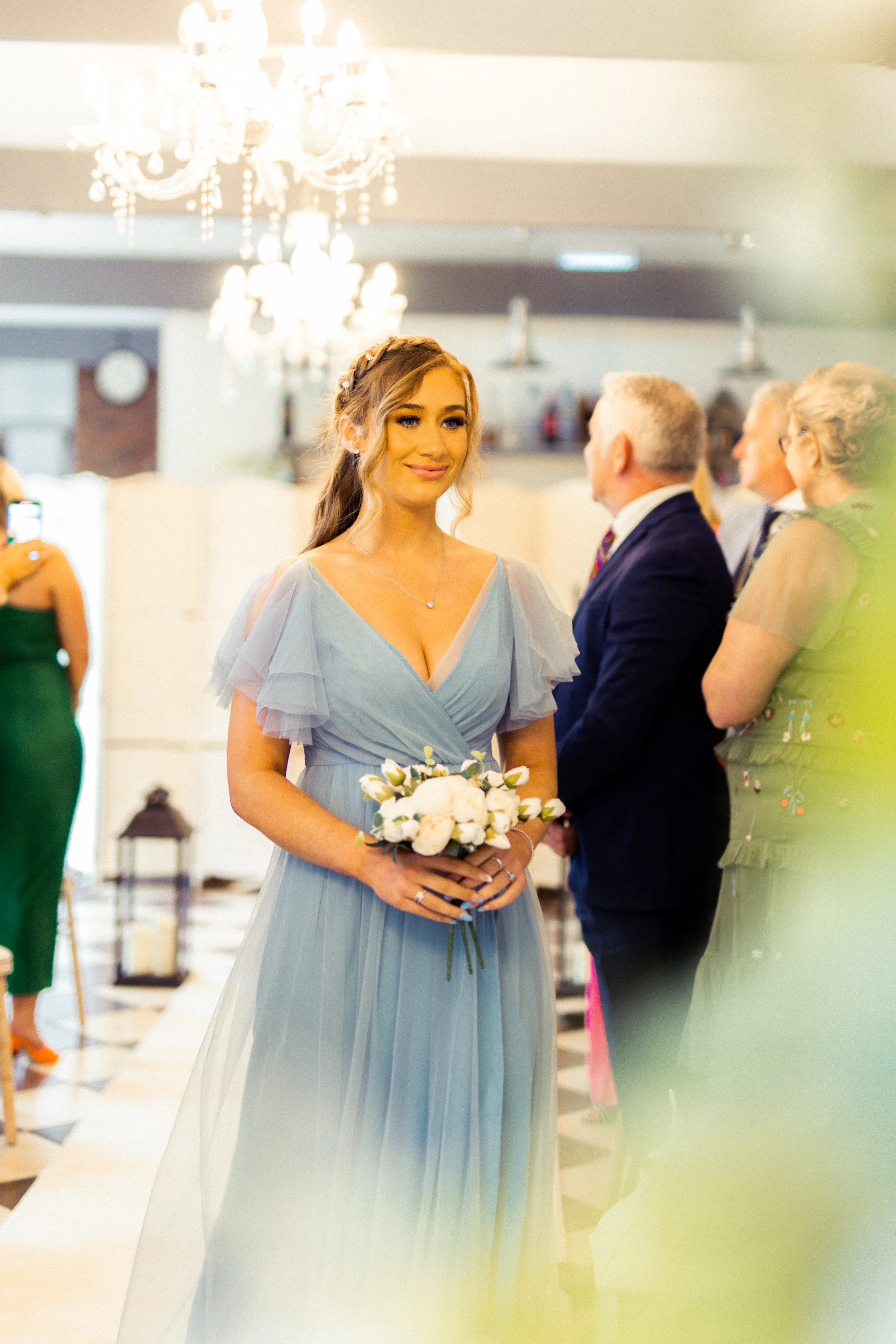 A woman in a light blue dress holding a bouquet of white flowers during a wedding ceremony.