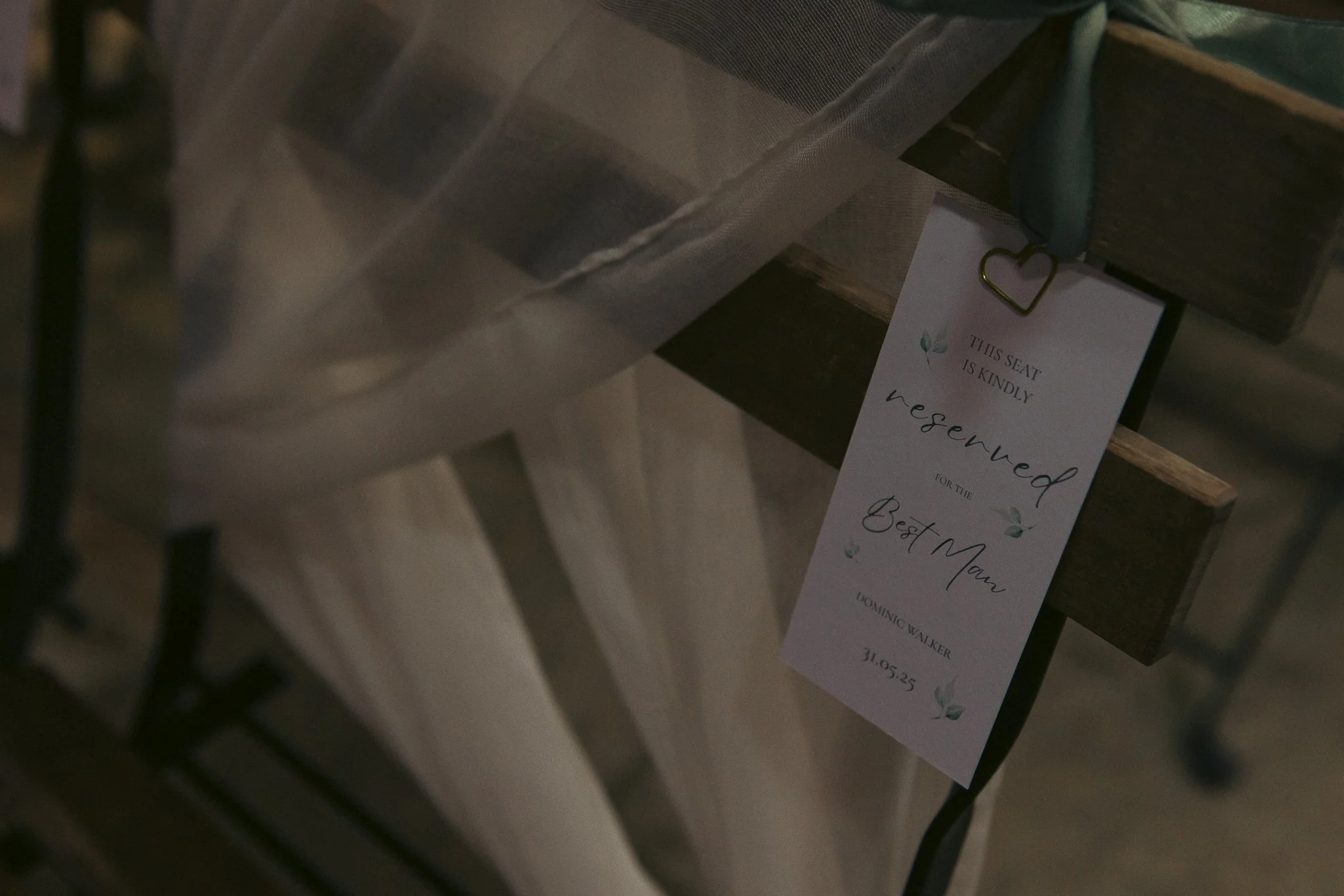 A reserved sign hanging on a chair at a wedding table with a note indicating it is for the groom, Dominic Walker, dated 31-05-25.