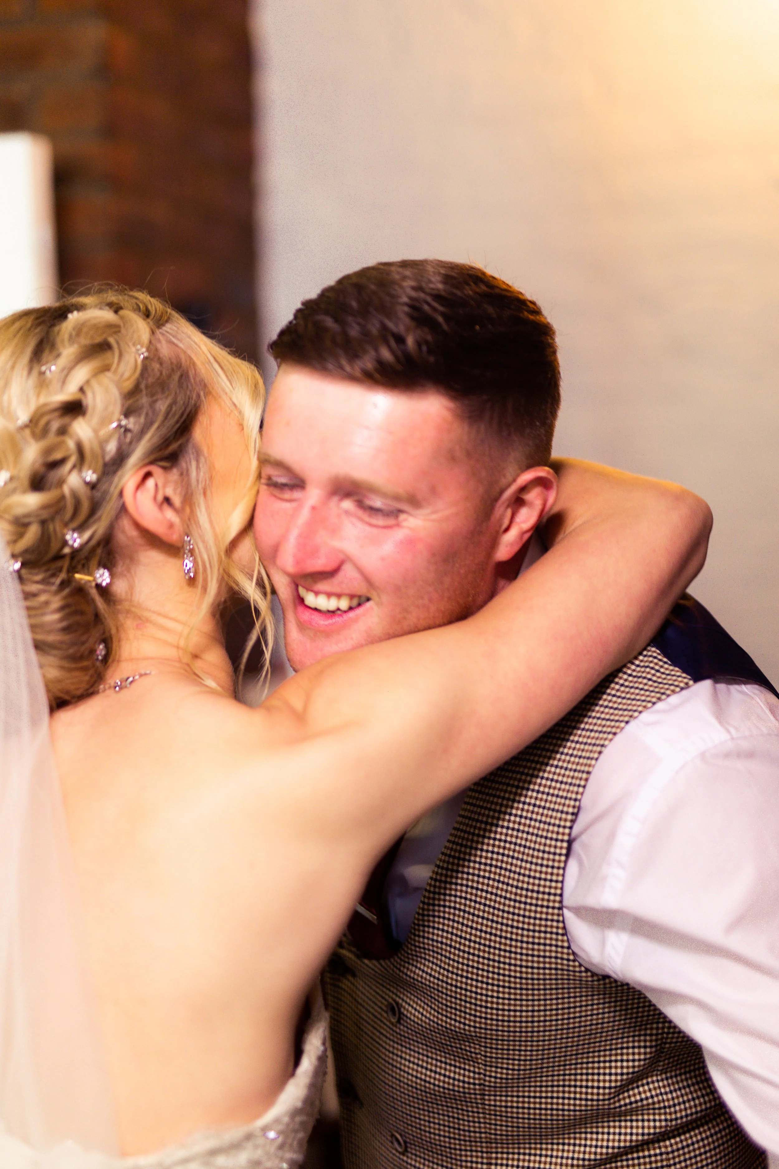 A happy couple, a bride and groom, hugging and smiling at each other during their wedding celebration.