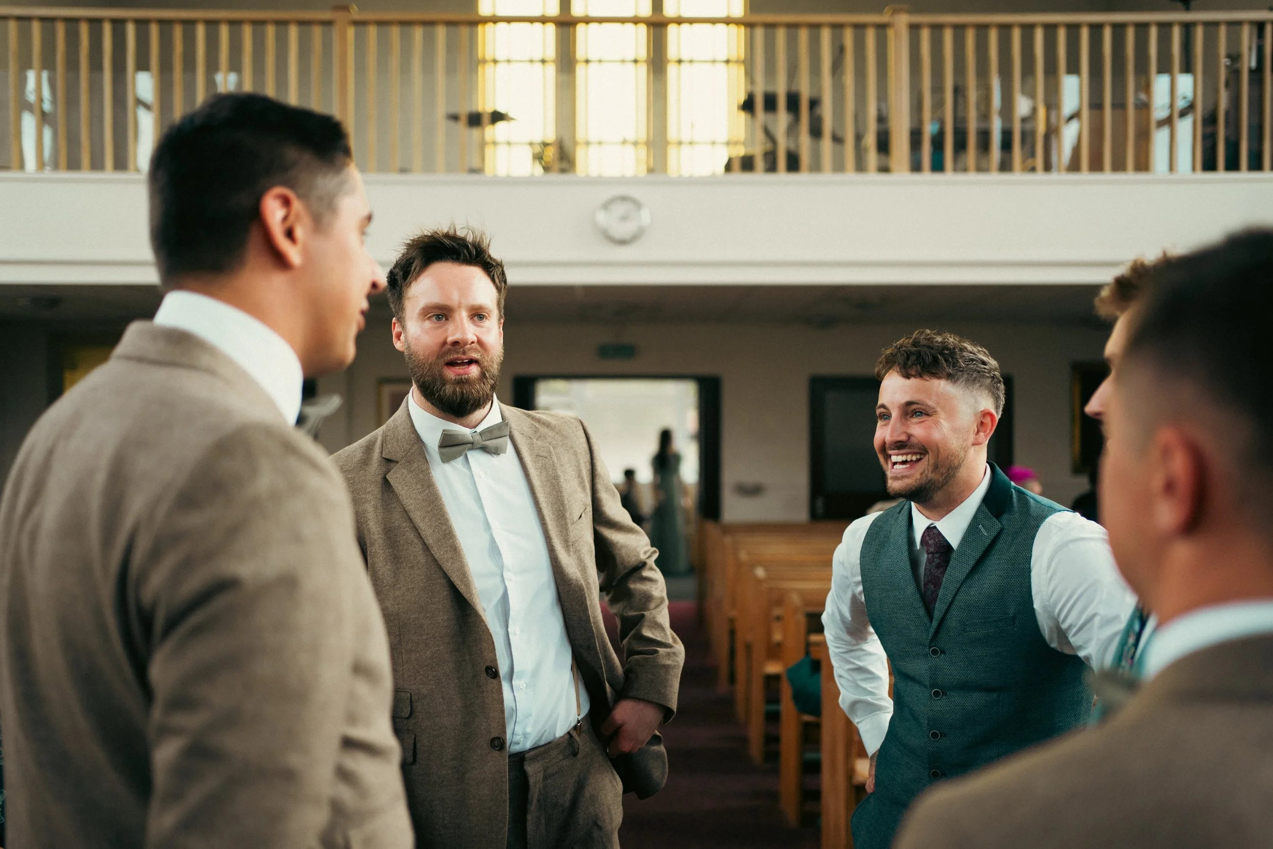 Group of five men in formal attire having a conversation inside a church or event hall
