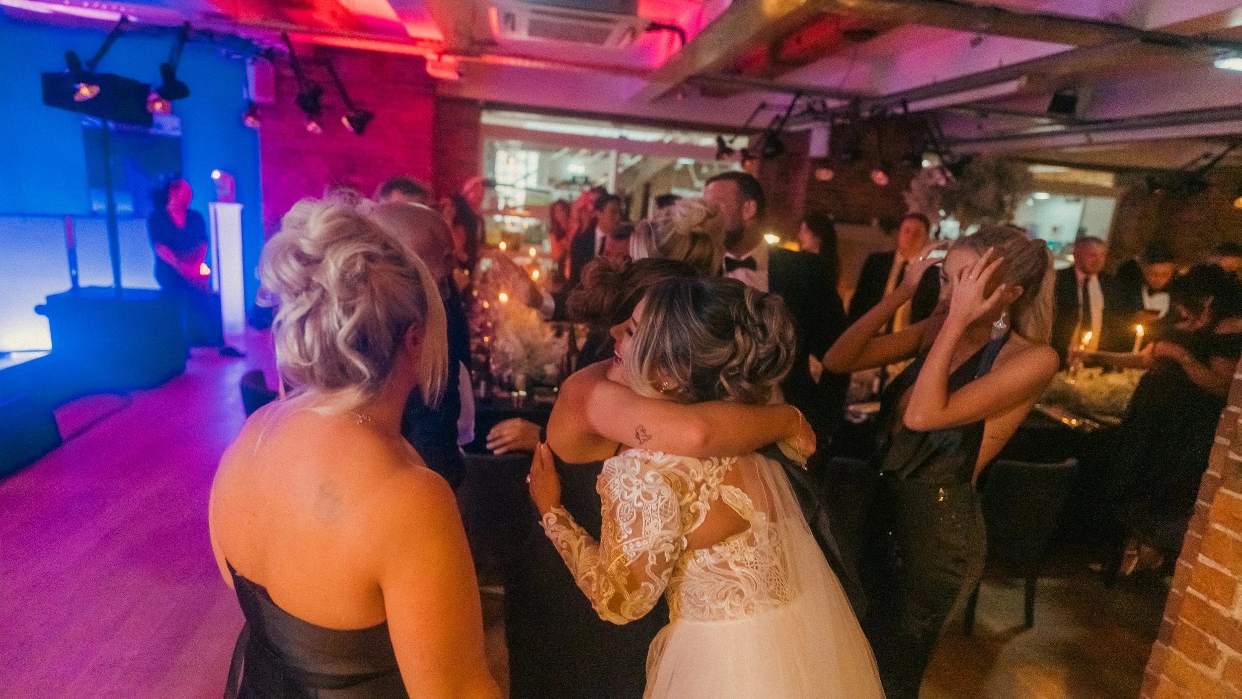 People dancing and hugging at a lively wedding reception.