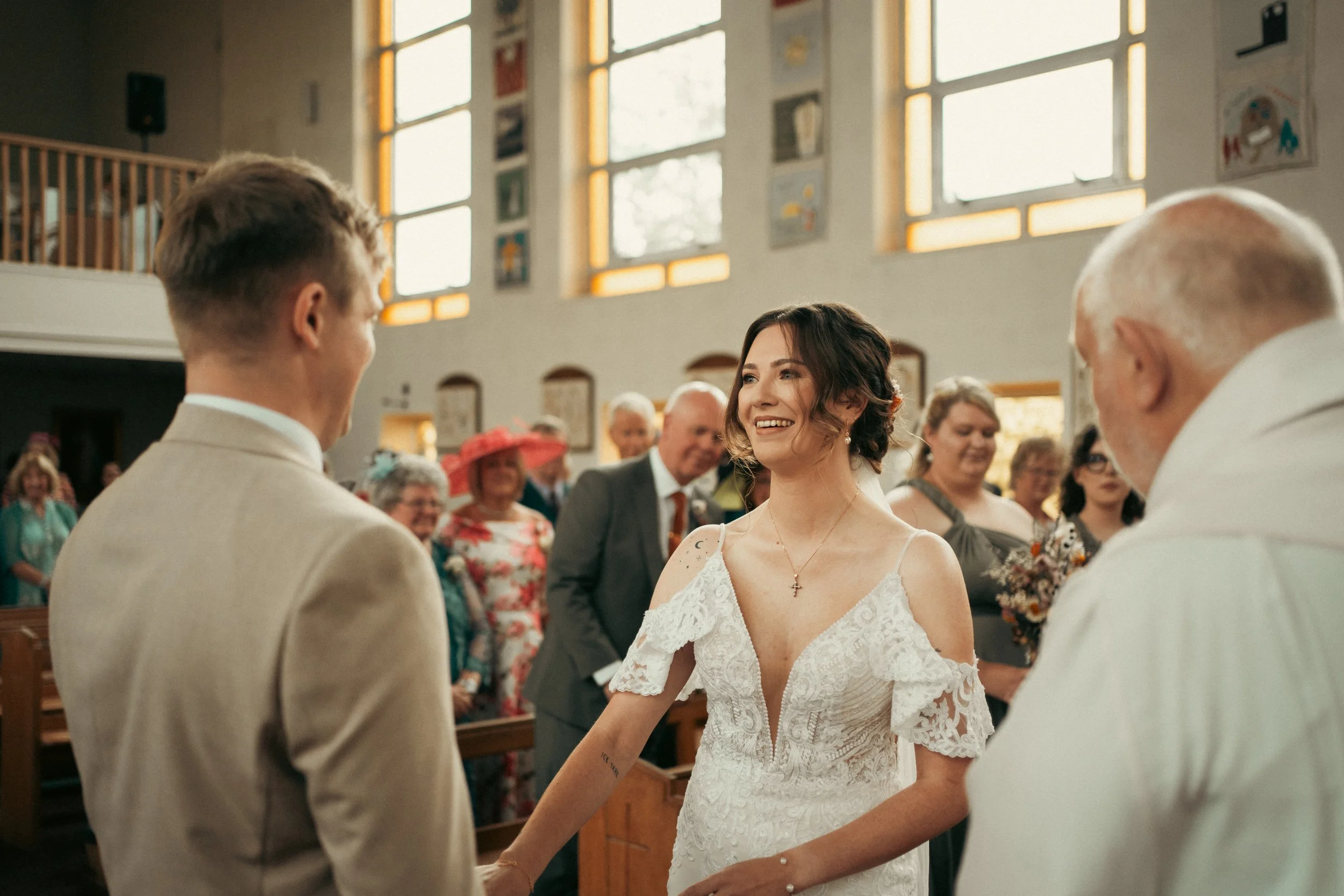 A bride and groom during their wedding ceremony inside a church, surrounded by friends and family.