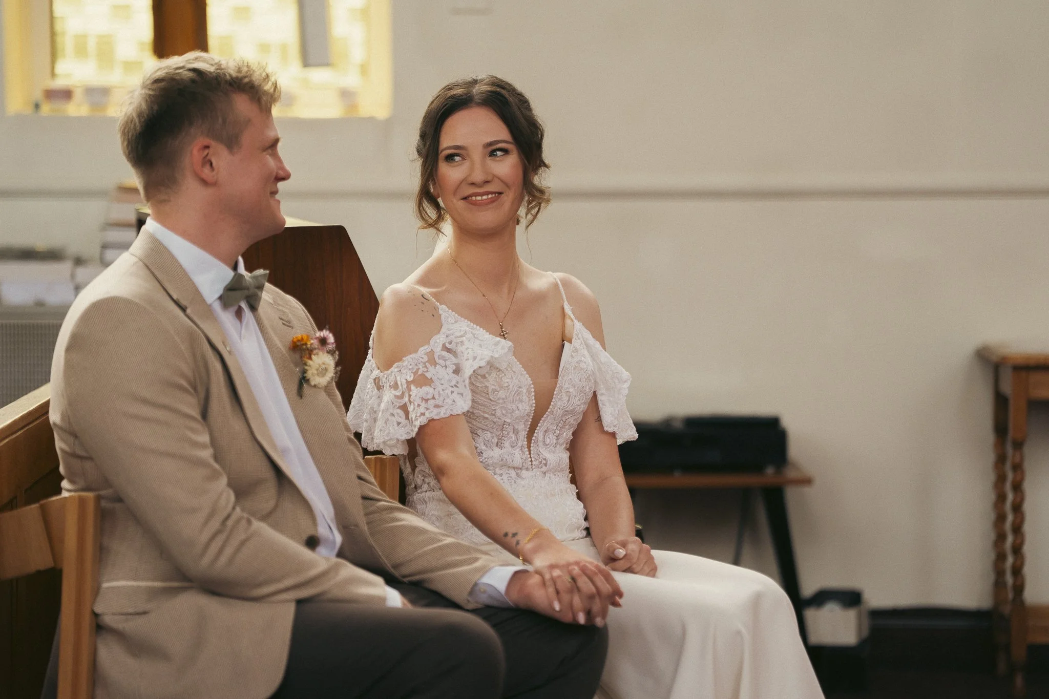 A bride and groom holding hands and smiling during a wedding ceremony inside a church.