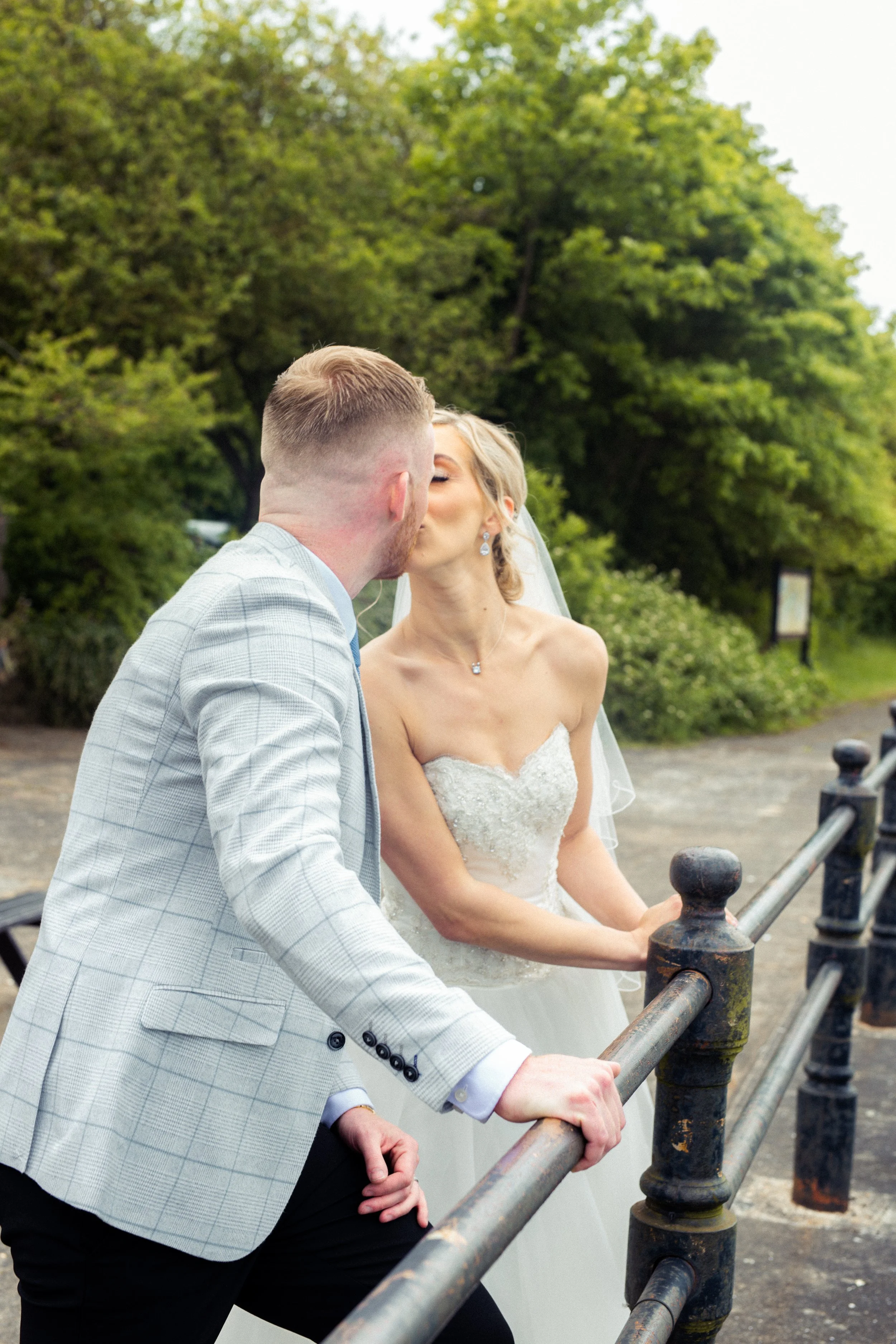 A bride and groom sharing a kiss outdoors on their wedding day.