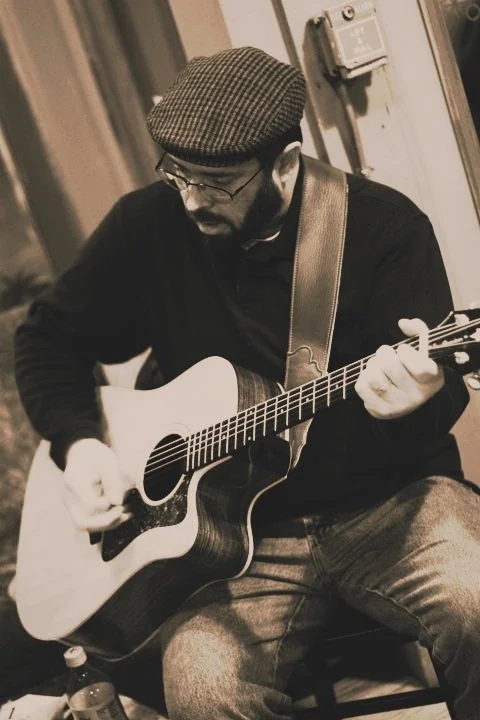 arte k playing an acoustic guitar