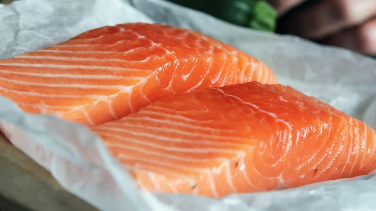 Two pieces of fresh salmon fillet on white paper