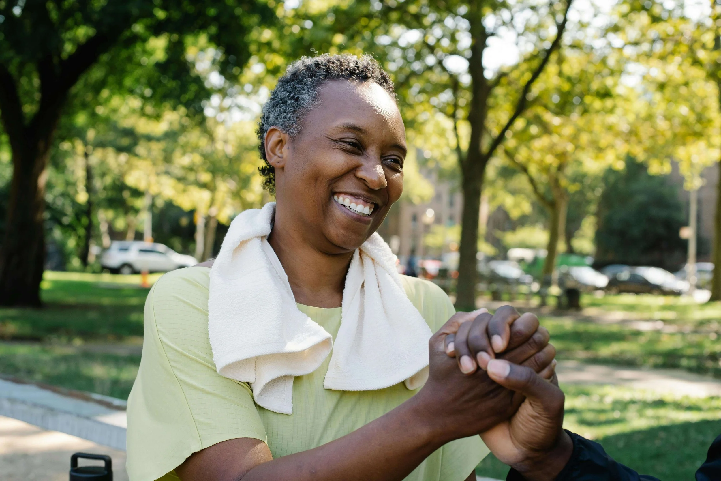 Woman smiling while holding hands with someone out of view, symbolizing connection and healing through family trauma therapy in Falls Church, VA.