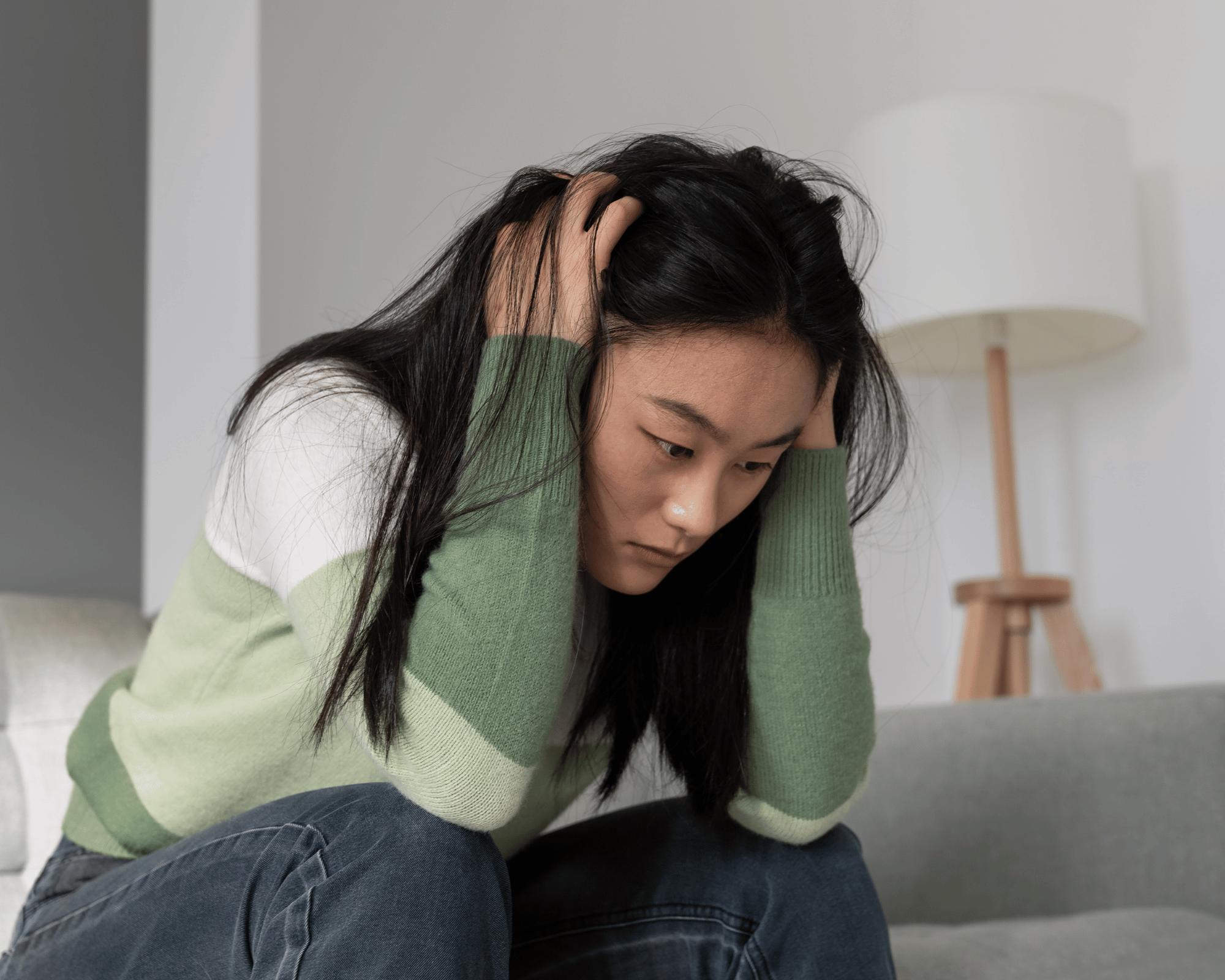 Image of stressed woman sitting on couch in Falls Church, VA to show trauma therapy and therapy for teen anxiety in New Orleans, LA, Connecticut and Virginia