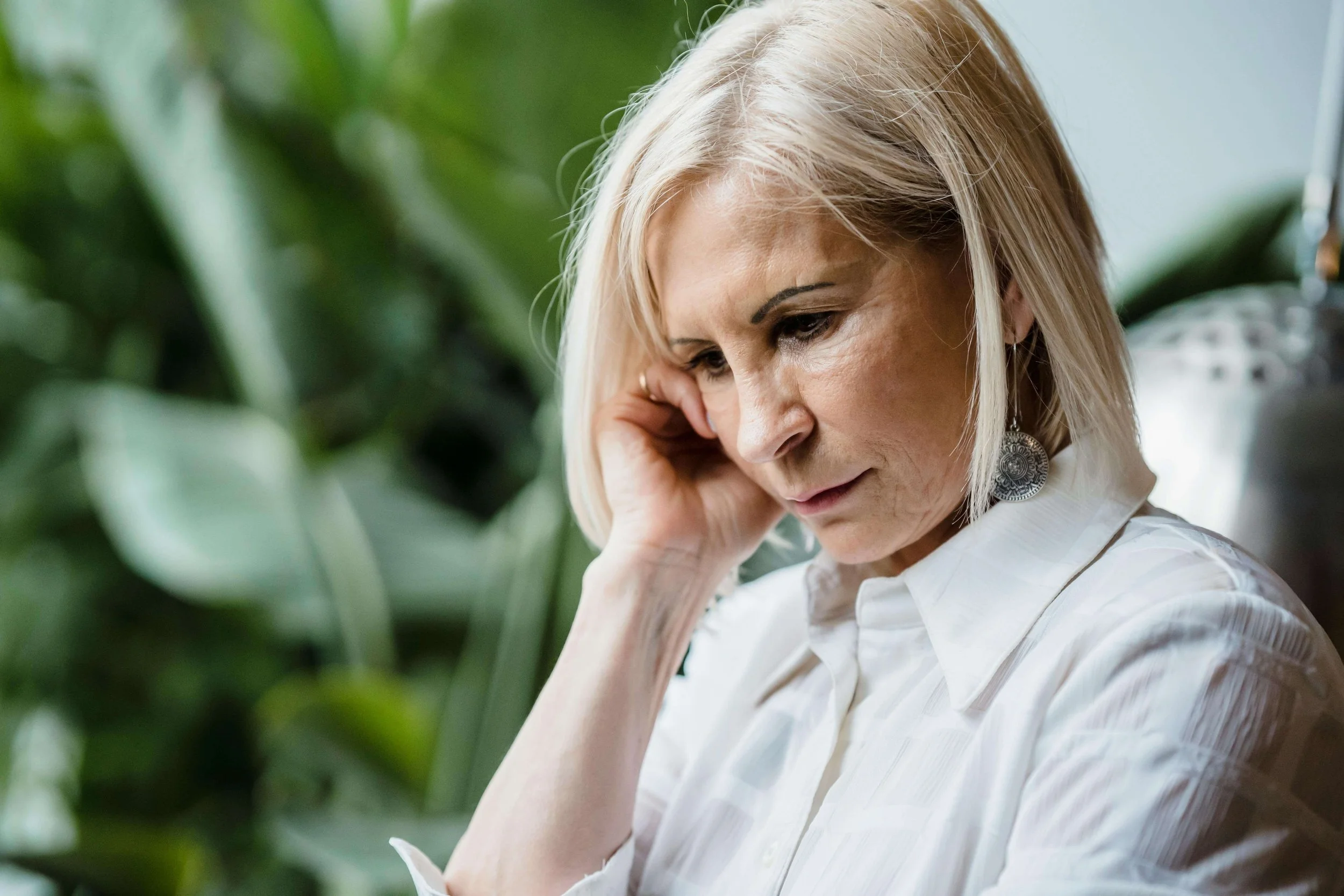 Older woman looking stressed and deep in thought, representing emotional strain addressed in trauma therapy for emotional parentification in Falls Church, VA.