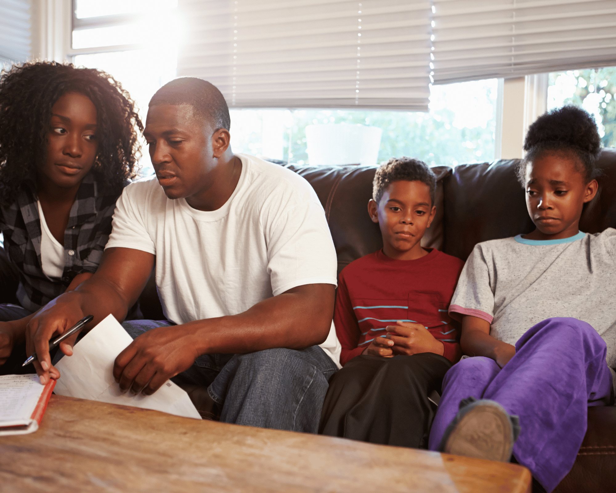 Image of worried son and daughter sitting next to stressed out parents to illustrate what is parentification trauma in Colchester, Connecticut and Virginia
