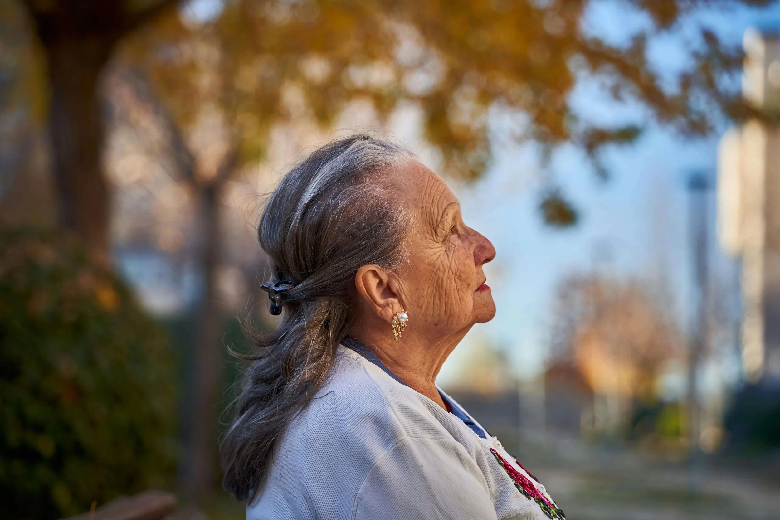 Older woman with gray hair looking up at the sky thoughtfully, representing self-reflection supported by culturally sensitive counseling in Falls Church, VA.