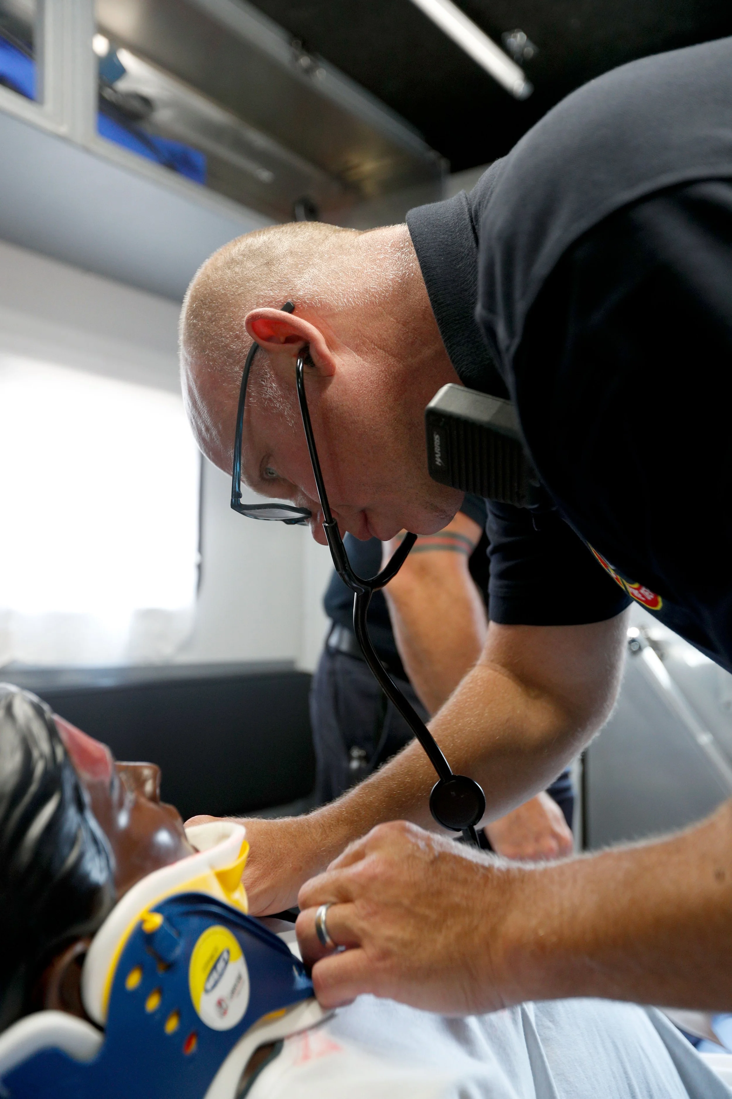 A man lying on a table with oxygen mask, receiving medical care from a healthcare worker in a hospital setting.