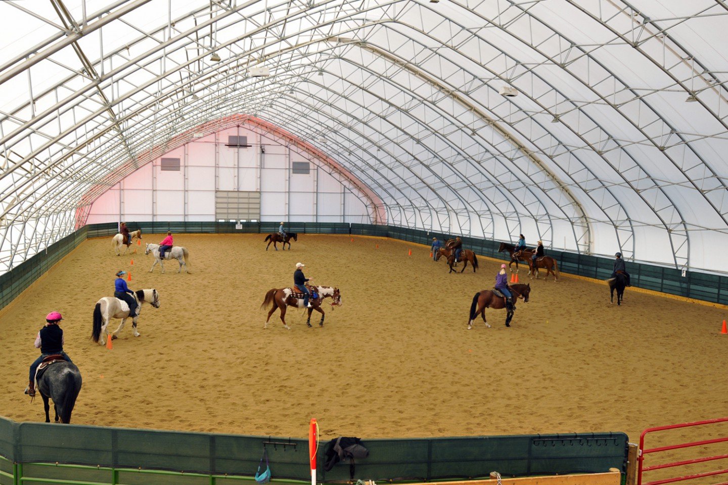 People riding horses in an indoor horse riding arena