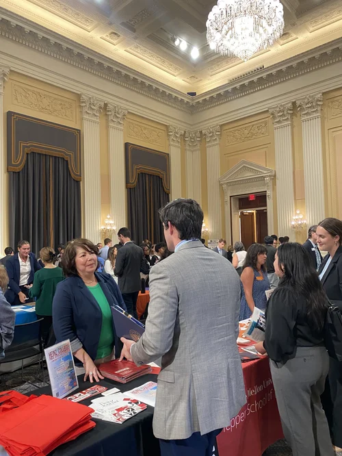Grad fair recruiter speaking with a student at a table