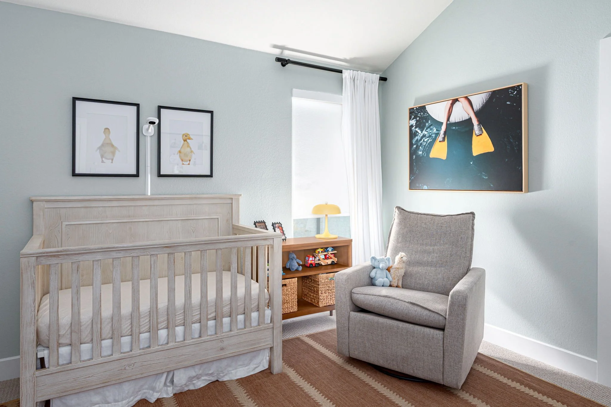 Light green and yellow nursery with duck photos and dark tan striped rug