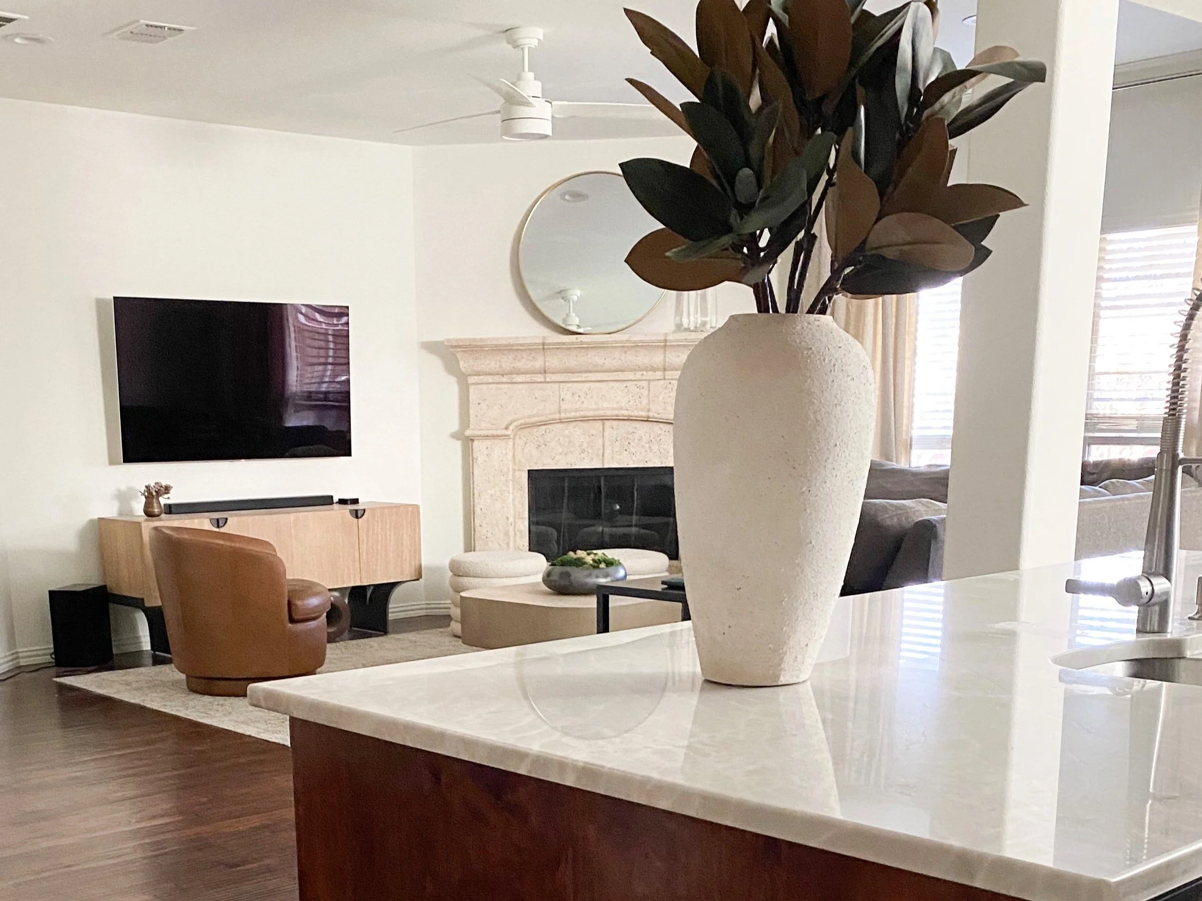 kitchen island with dark wood cabinets and white quartzite countertop with large vase of magnolia branches on top