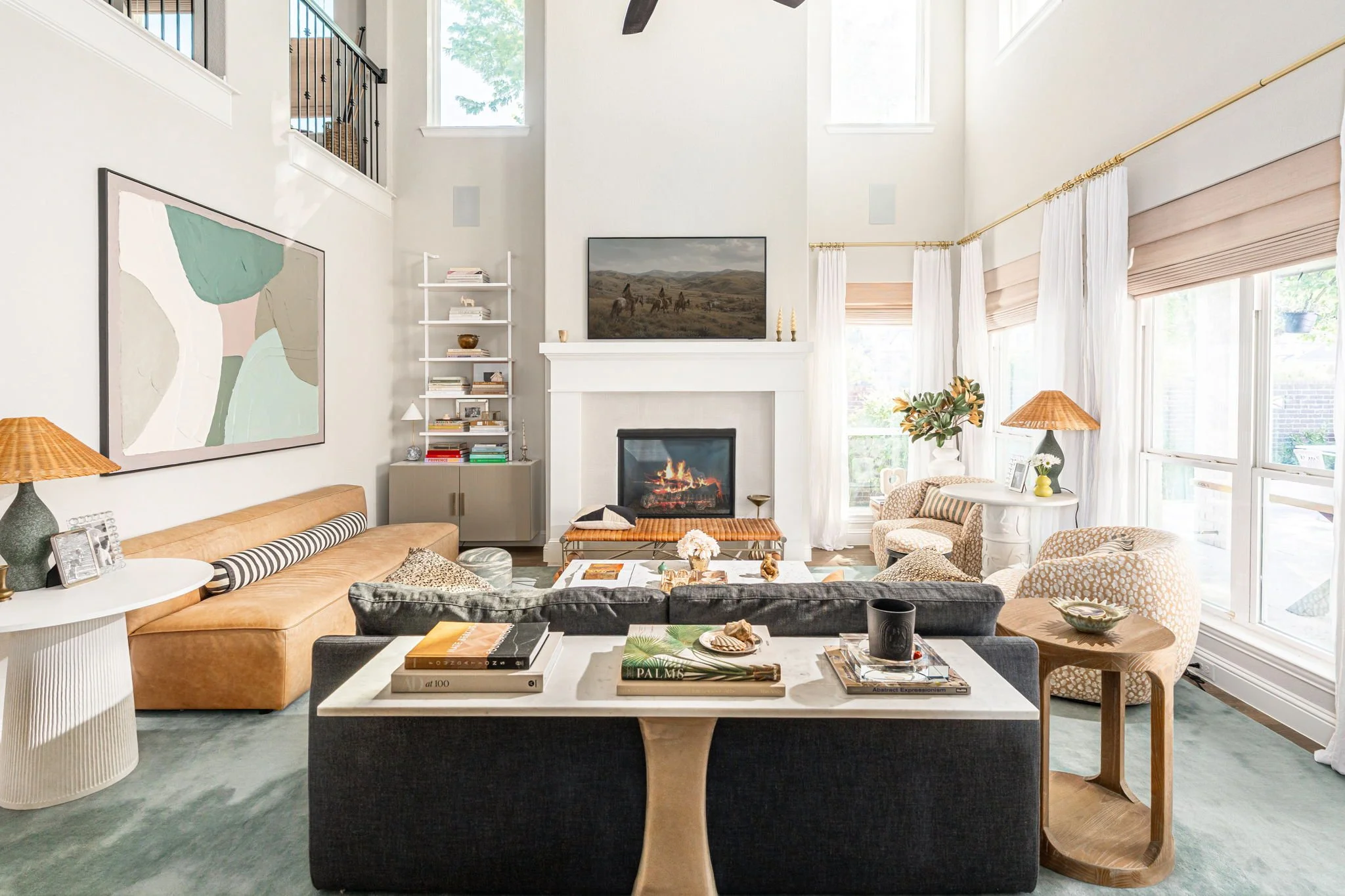 living room with black sofa, brown leather sofa, blue rug and blue and green abstract art