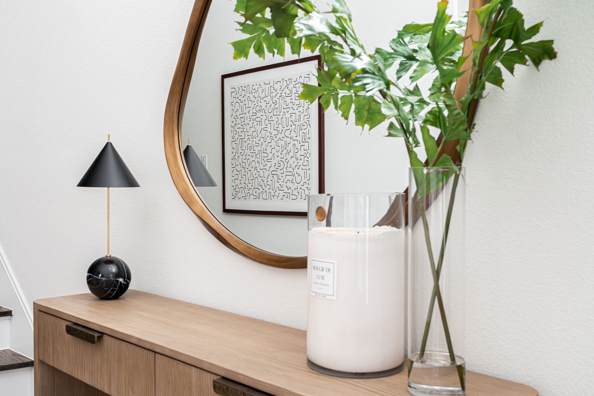 Console table with abstract art reflected in round mirror  