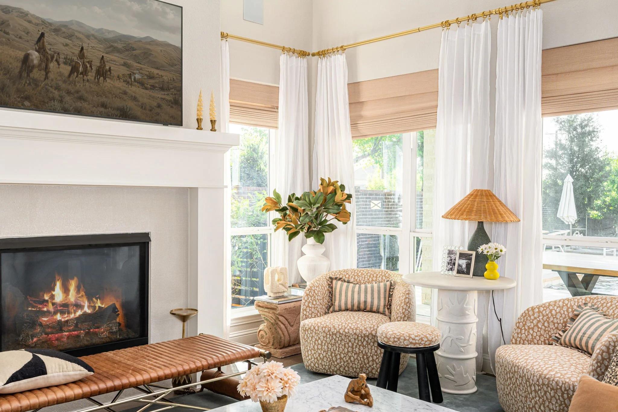 living room with leather daybed, matching leopard print chairs and white table topped with blue lamp. 