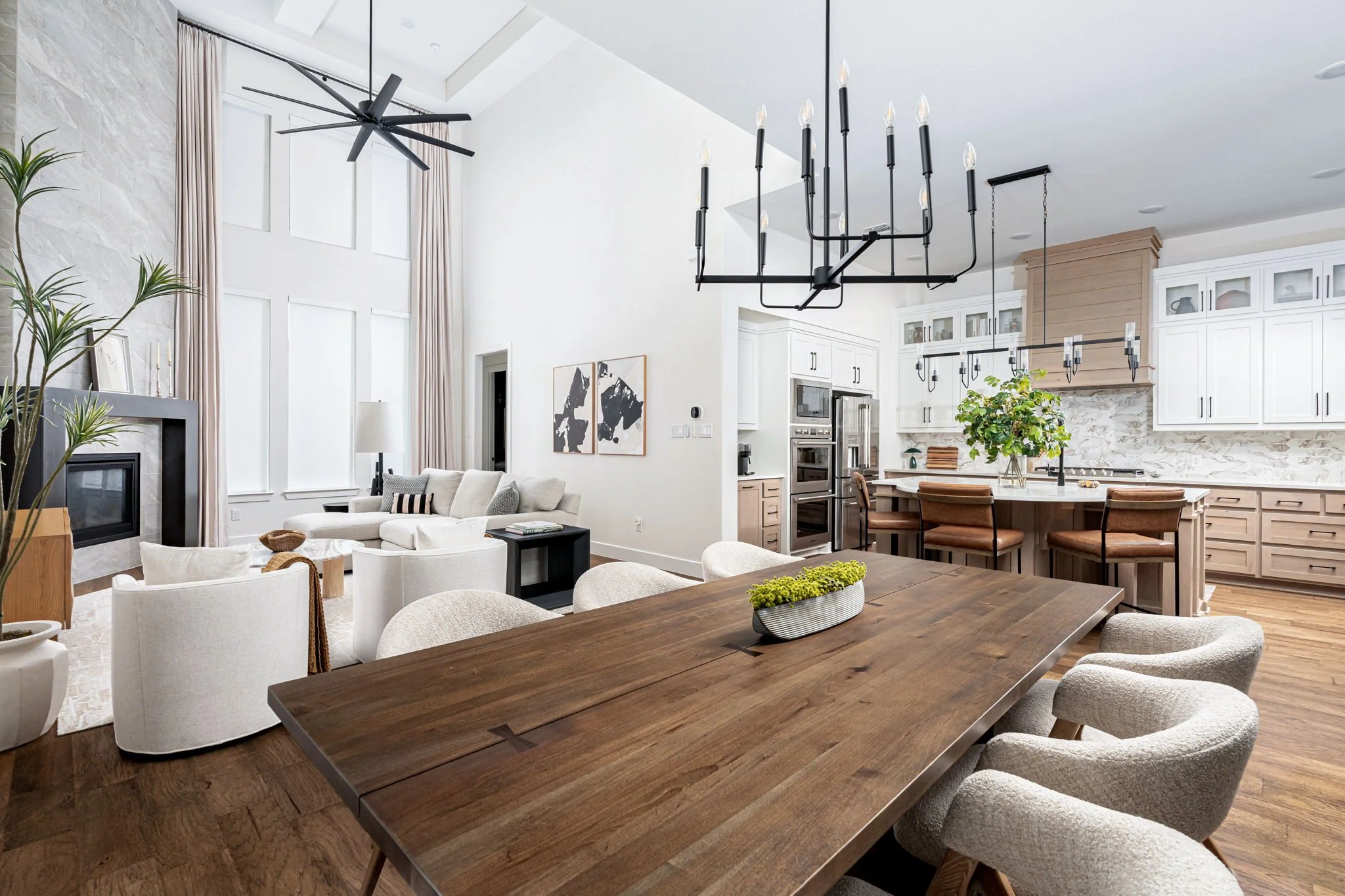 Great room in prosper texas with dark wood dining table upholstered dining chairs larrge kitchen with wood cabinetry