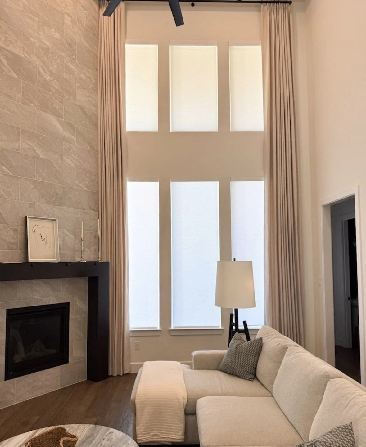 Living room in Prosper, Texas, after interior design service by Brooke Bundy Designs. Custom drapes, new art, candles, a couch, throw pillows, blanket, lamp.