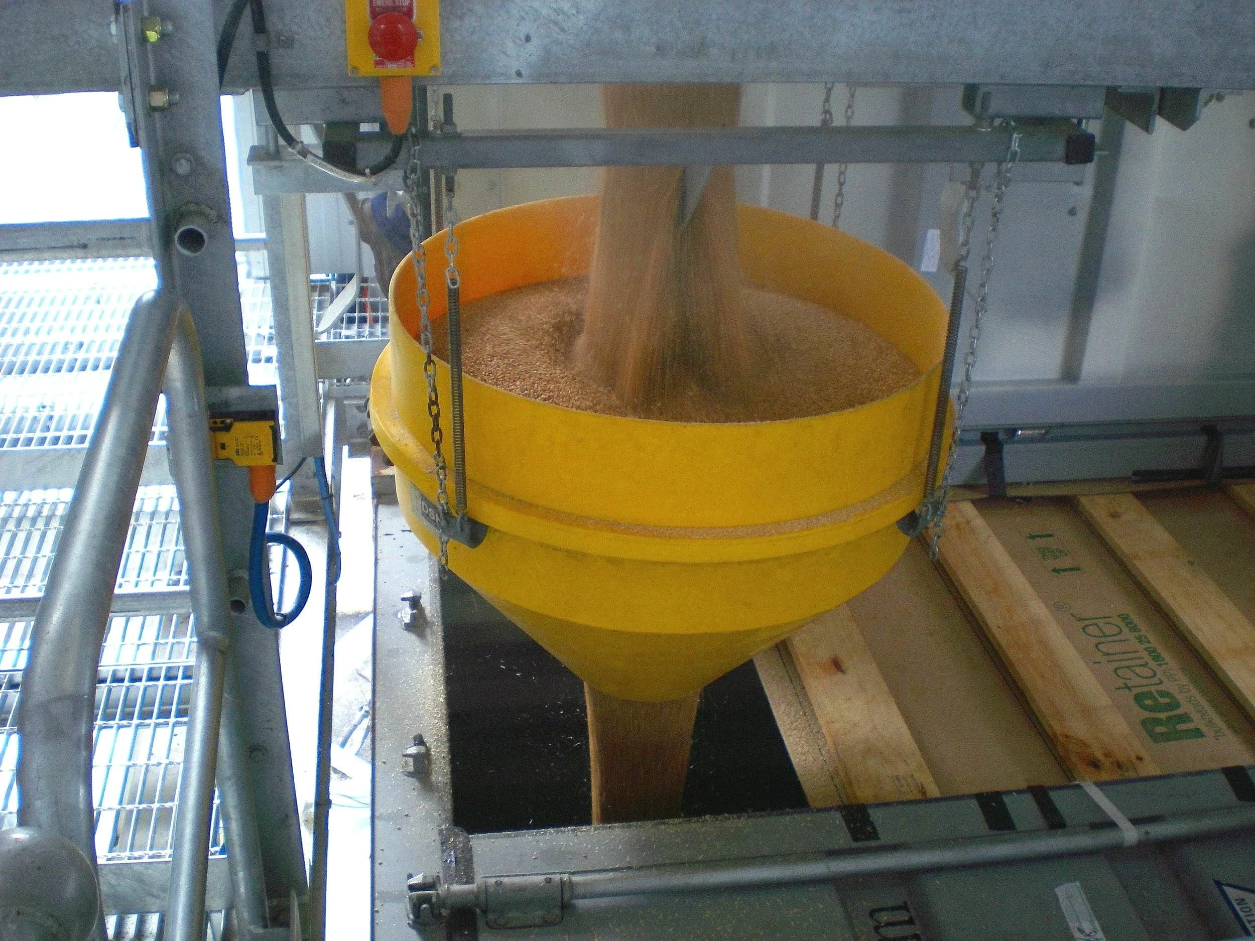 A yellow dust suppression hopper releasing grain or similar material.