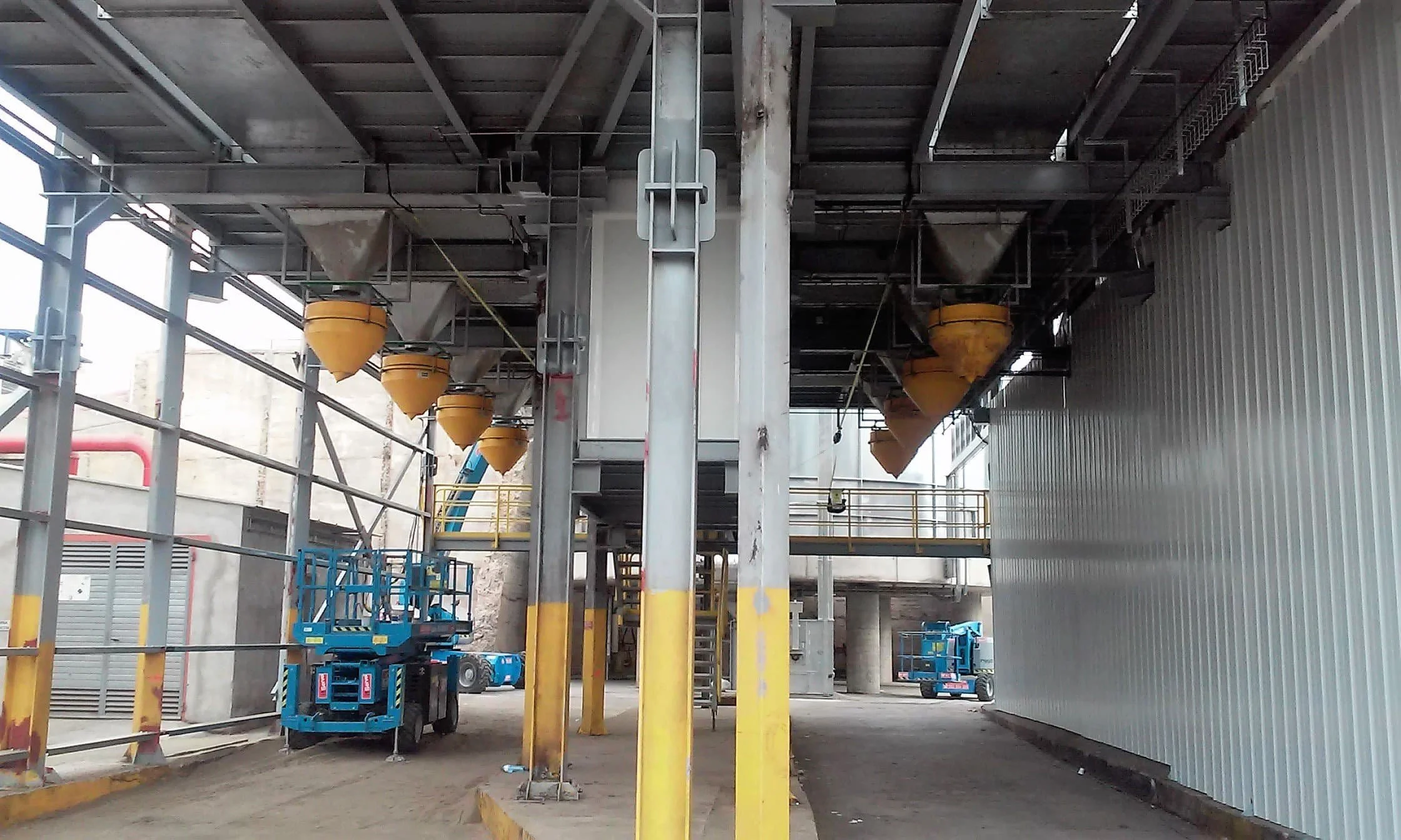 Industrial construction site with multiple yellow dust suppression hoppers.