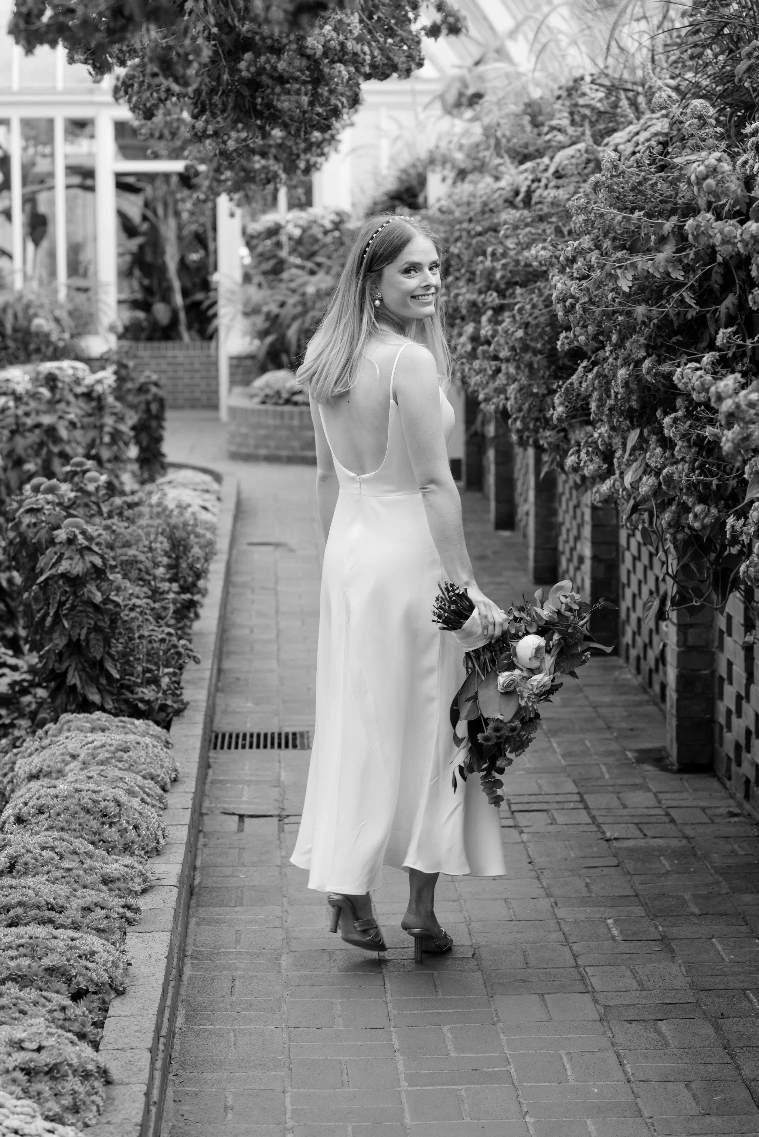 Image of bride smiling over her shoulder at Phipp's Conservatory. By Joe Appel Photography