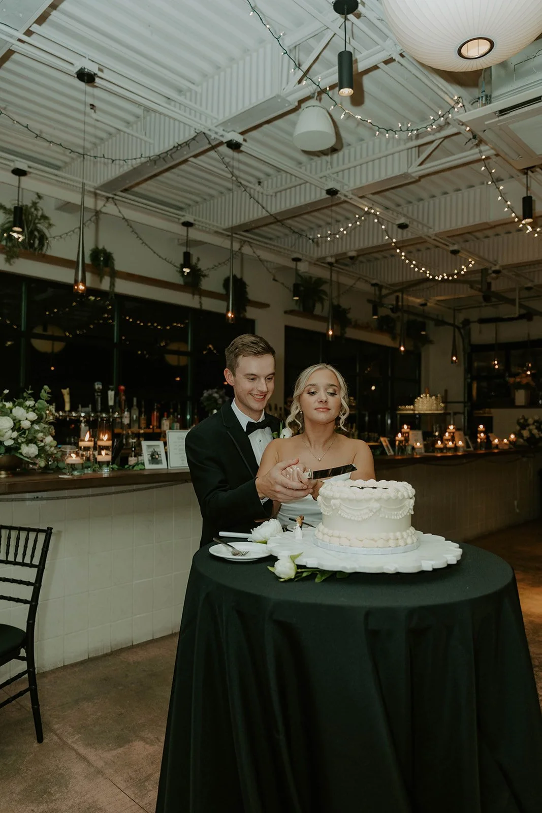 Happy couple, cutting their cake, in front of the upstairs bar at Over Eden.