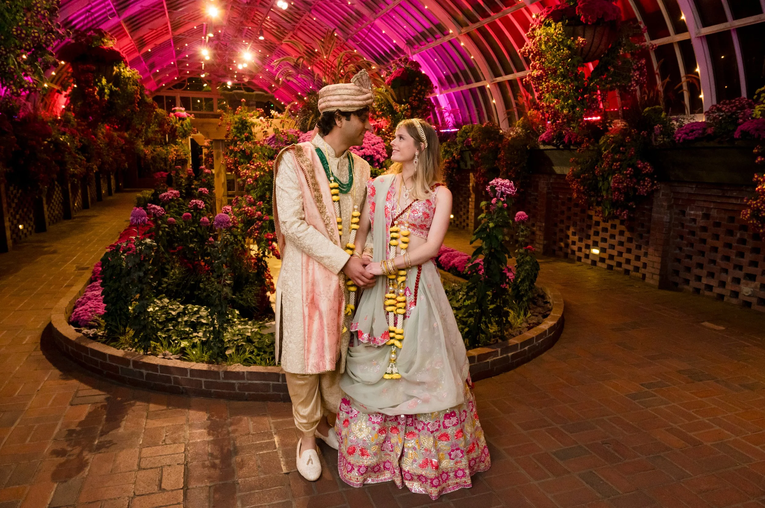 Image of happy couple smiling at each other in a beautifully lit Phipp's Conservatory. Photo by Joe Appel Photography.