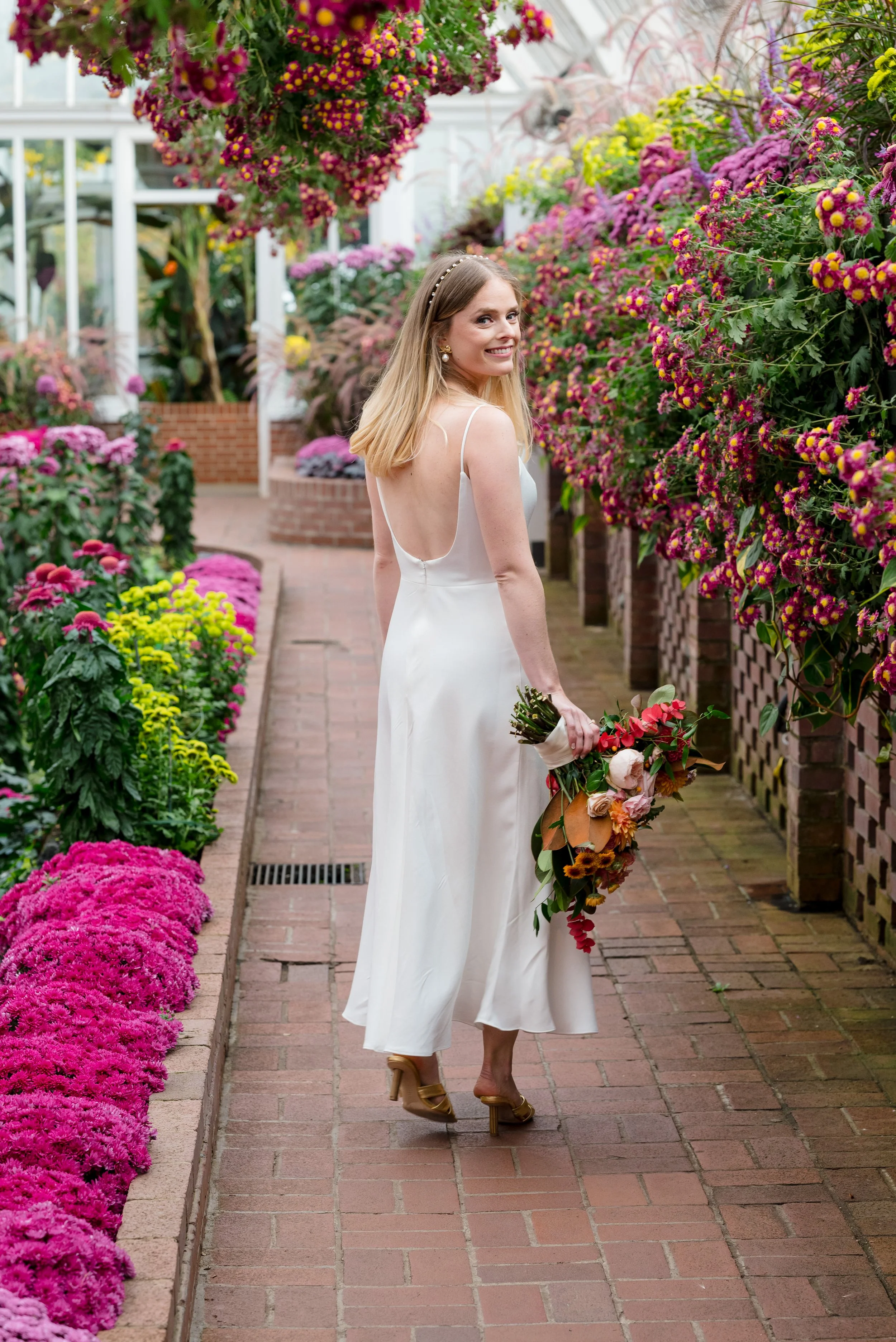 Image of smiling bride surrounded by beautiful florals at Phipp's Conservatory. Photo by Joe Appel Photography.
