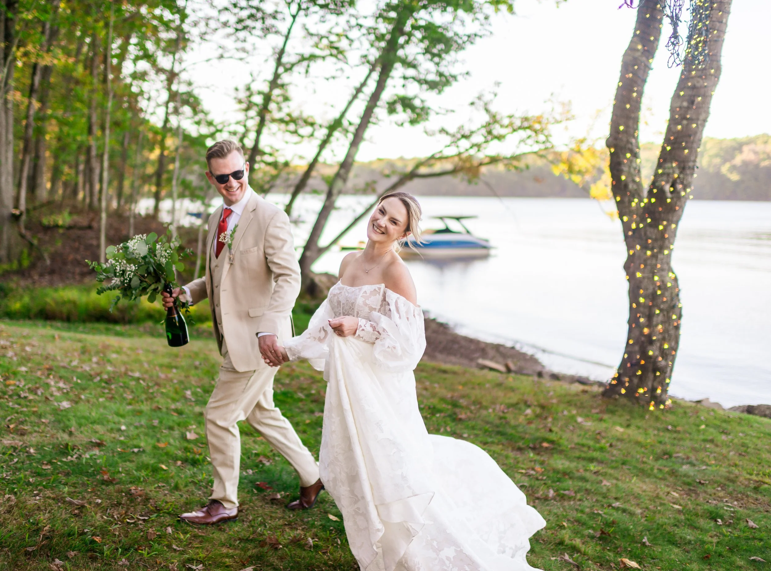 Photo of happy Bride and Groom holding hands and walking near the lake; from a private estate wedding in Deep Creek, VA. By Rey Lopez Photo