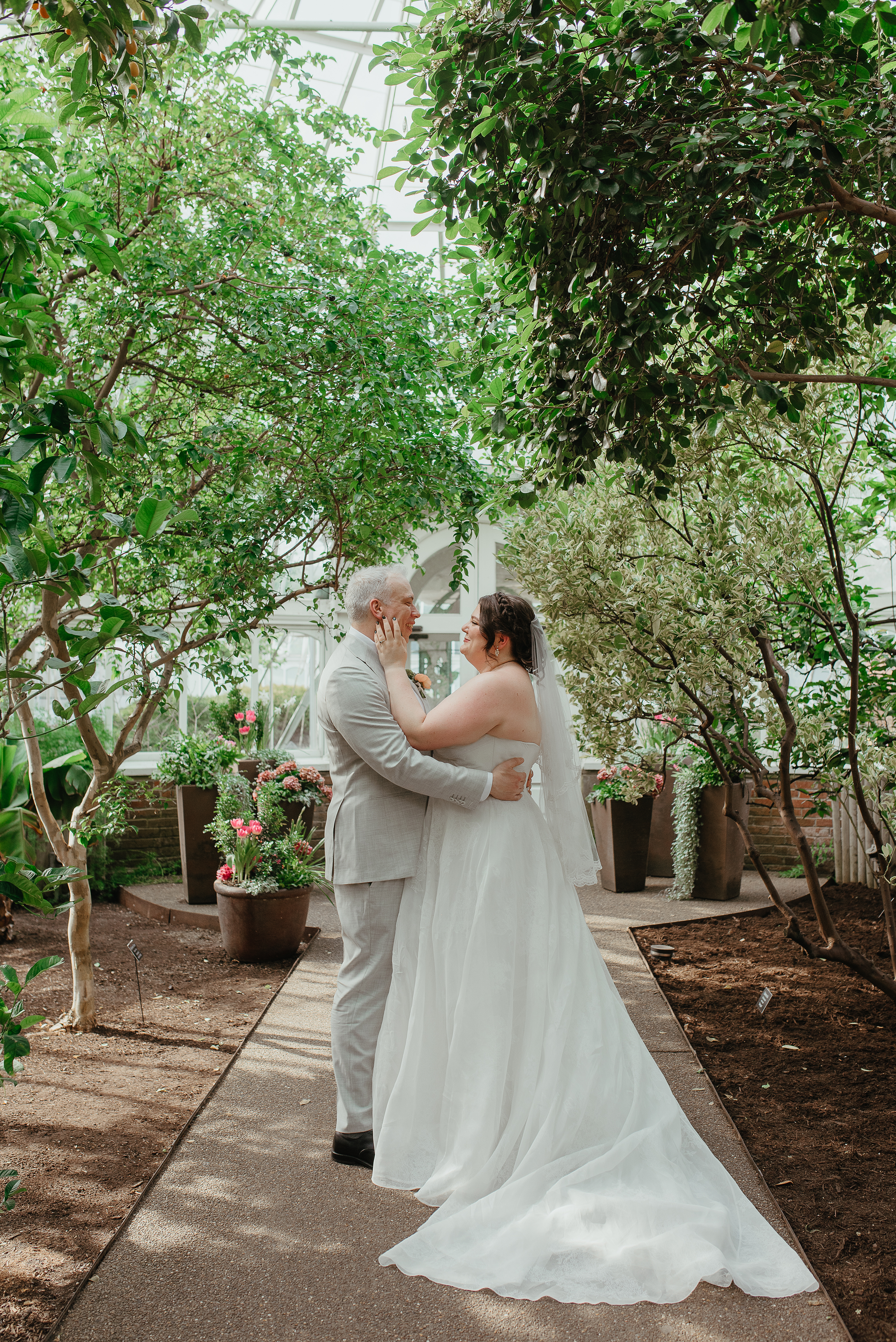 Image of happy couple smiling at each other in a courtyard at the beautiful Phipp's Conservatory. Photo by Jess Vogelsang.