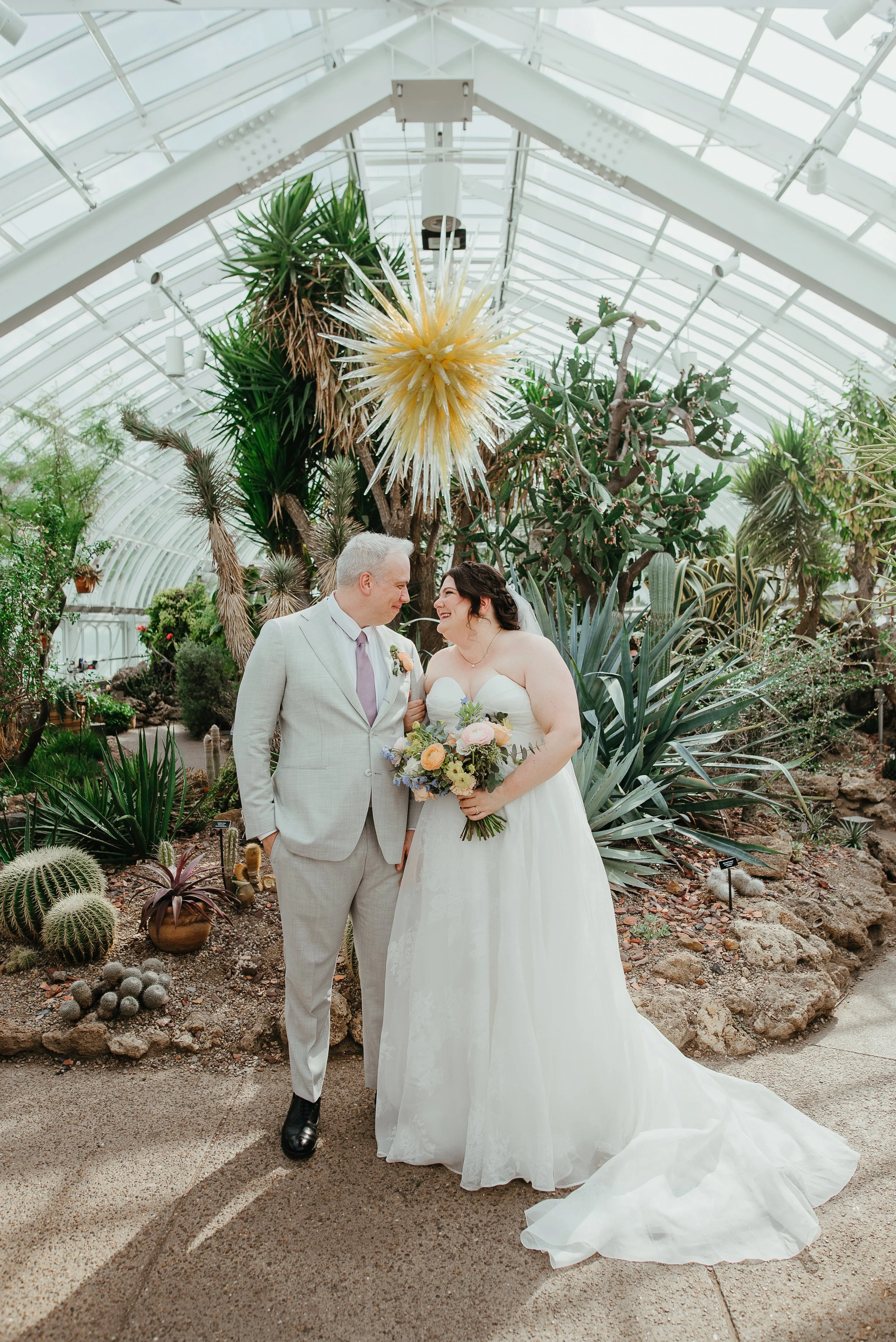Image of happy couple smiling at each other in the beautiful Phipp's Conservatory. Photo by Jess Vogelsang.
