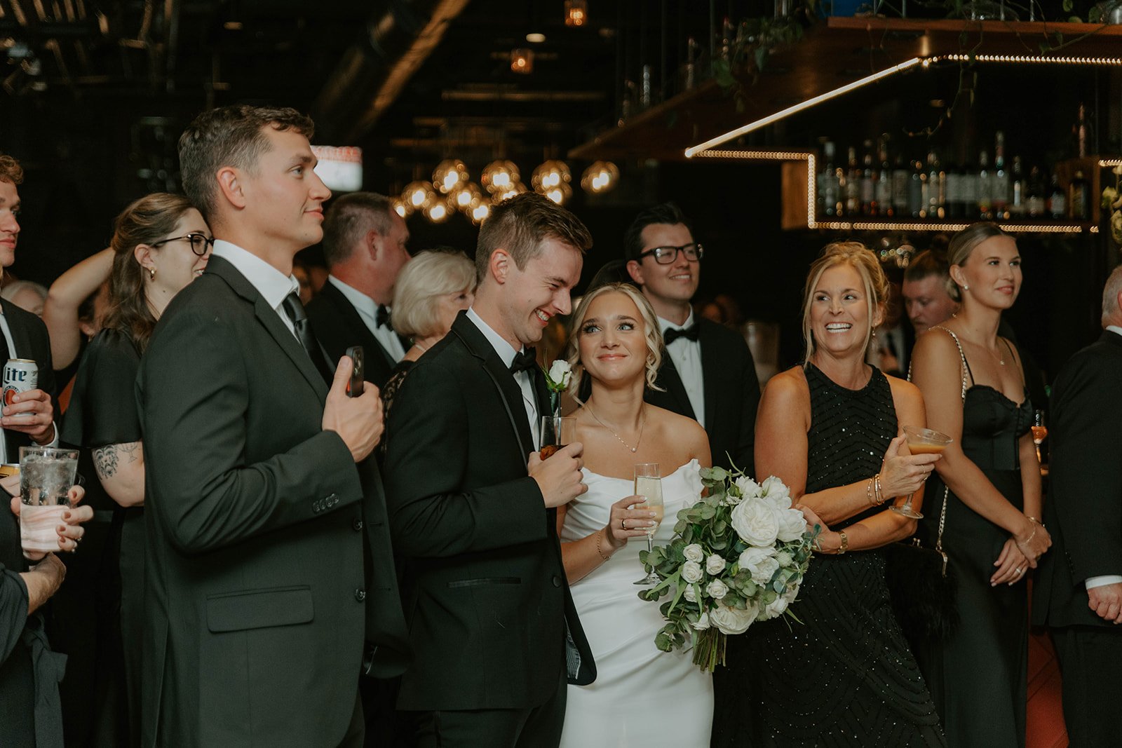 A happy bride looking at her laughing husband during speeches in the downstairs bar at Over Eden.