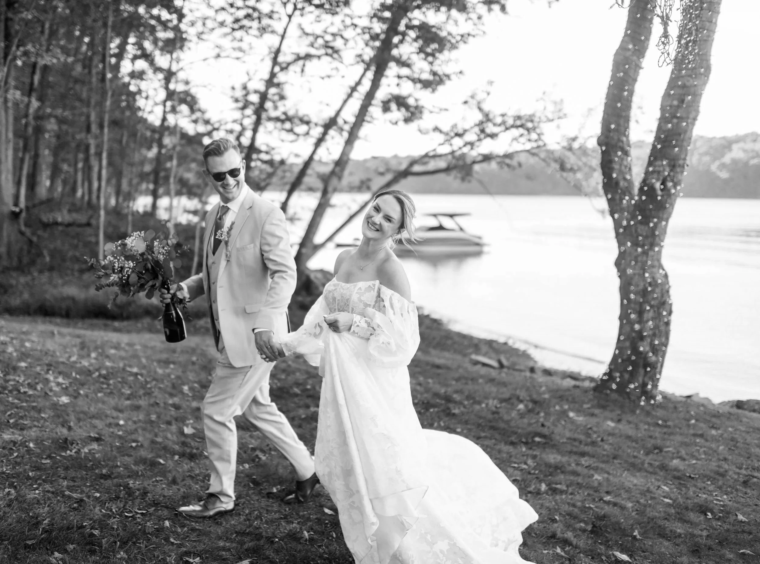 Photo of happy Bride and Groom holding hands and walking near the lake; from a private estate wedding in Deep Creek, VA. By Rey Lopez Photo