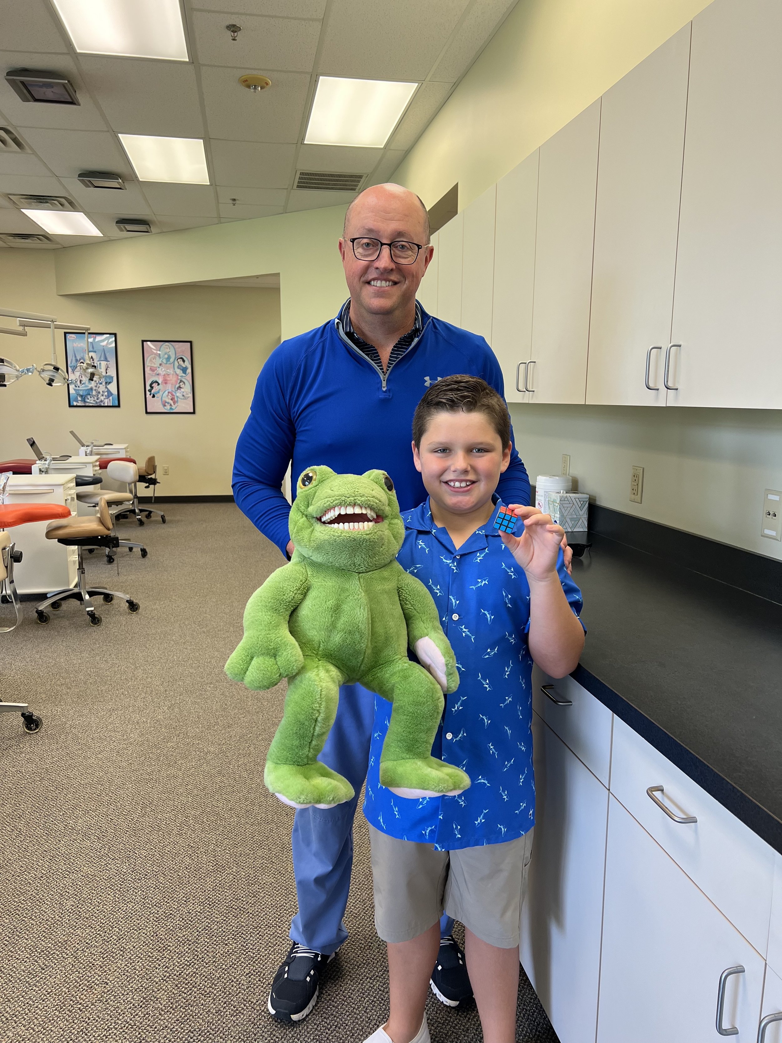 Dr. Brent Caple, DDS of Rogers, AR with happy patient and stuffed Mr. Frog.