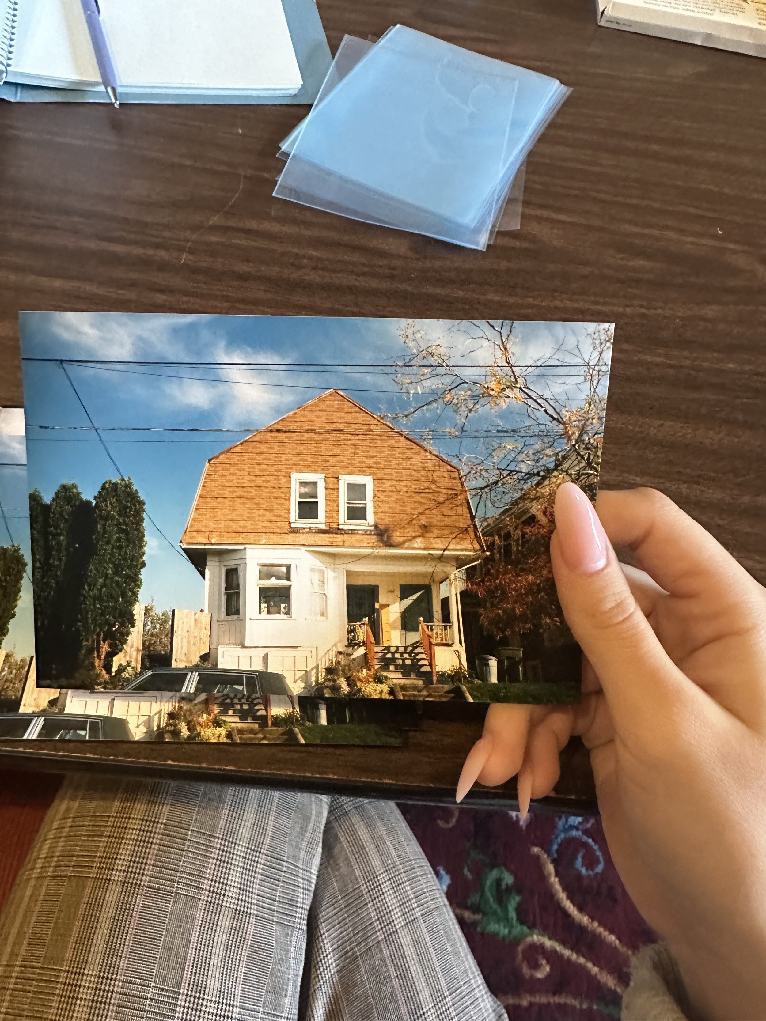 A hand holds a photo of a home featured in the Cornerstones Project.