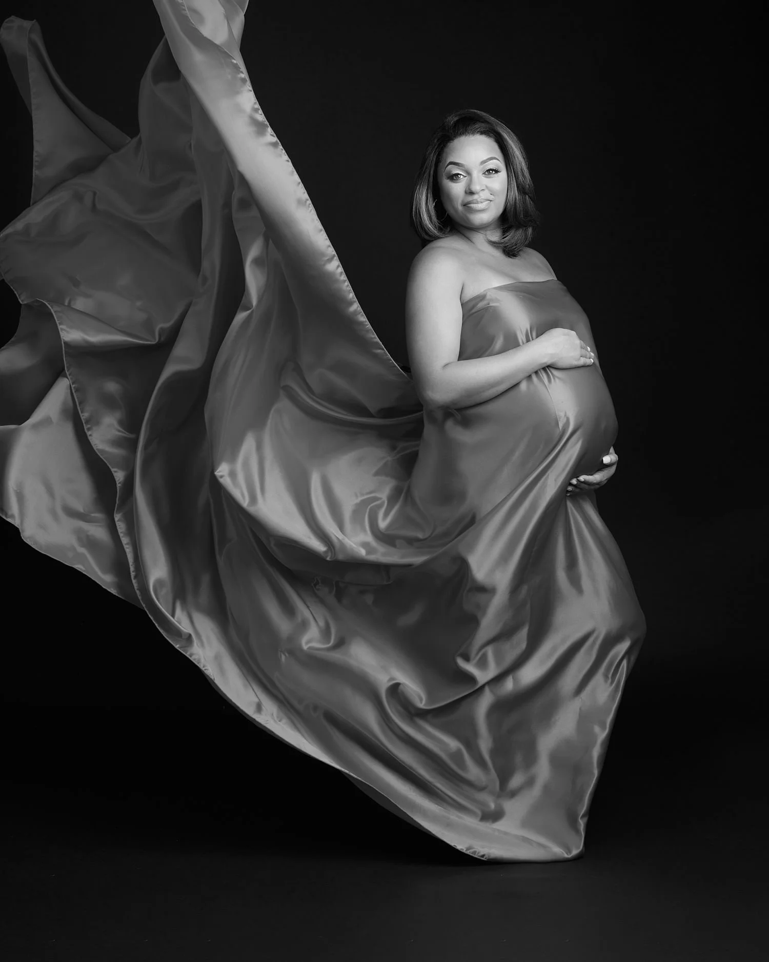 Creative black and white maternity portrait with flowing silk fabric and elegant pose