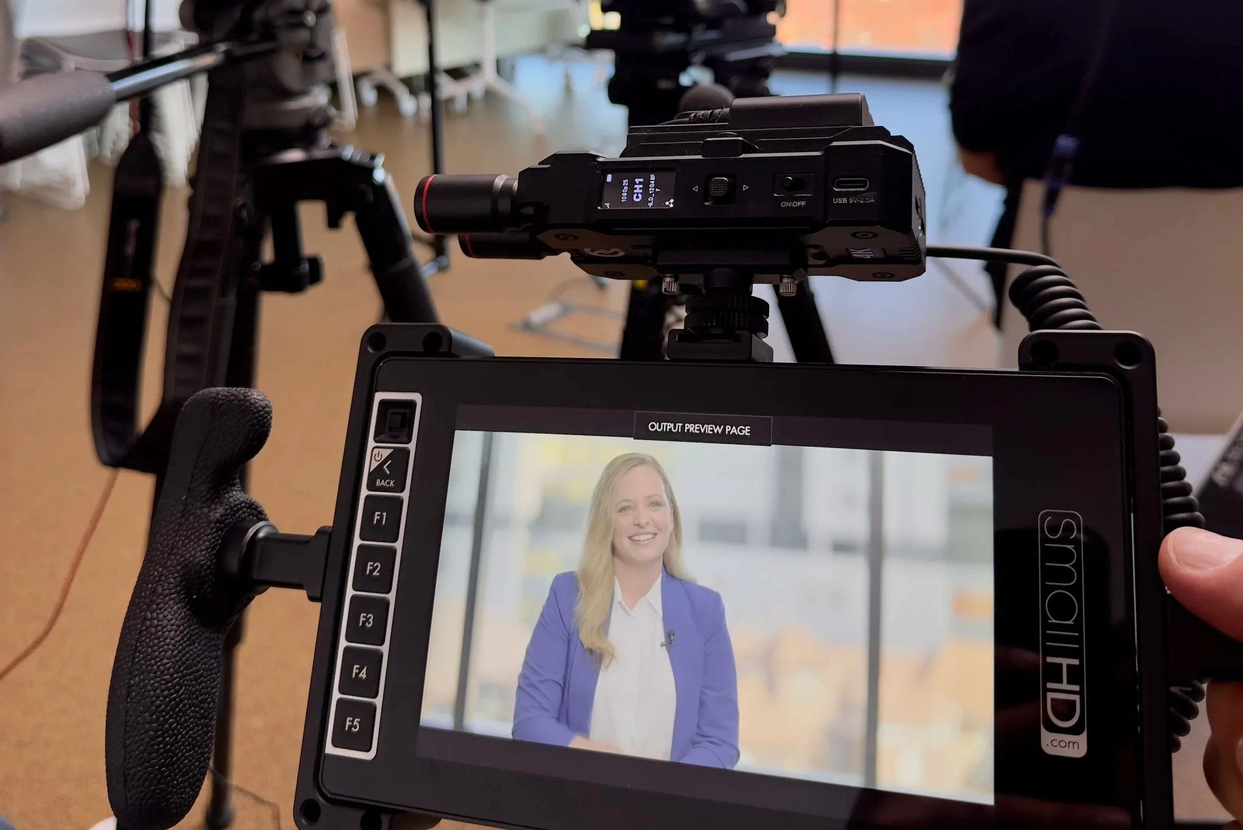 Camera operator filming corporate interview in Sydney with monitor and lighting
