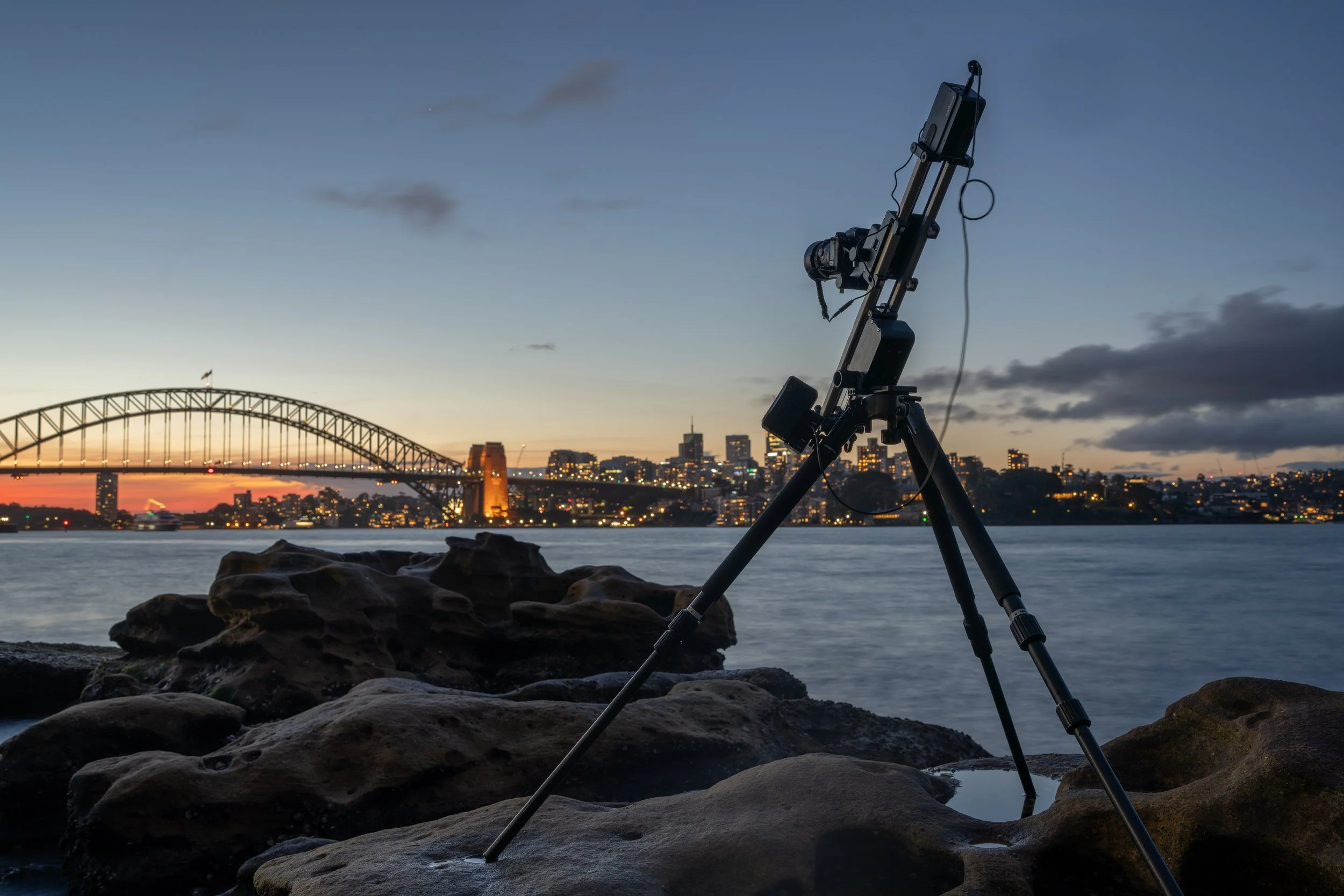 Timelapse camera setup on tripod capturing Sydney Harbour at sunset with long exposure technique