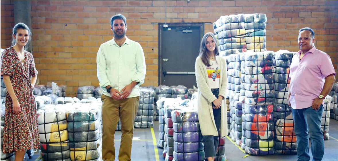 Googfair team standing in front of recycled clothing